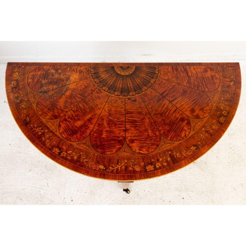 Ein Kartentisch aus Satinholz und Mahagoni aus dem späten 19. Jahrhundert. Im geschlossenen Zustand zeigt der Deckel eine exquisite florale Intarsienarbeit. Beim Öffnen kommt ein grüner Filz zum Vorschein. Eine verborgene Schublade lässt sich