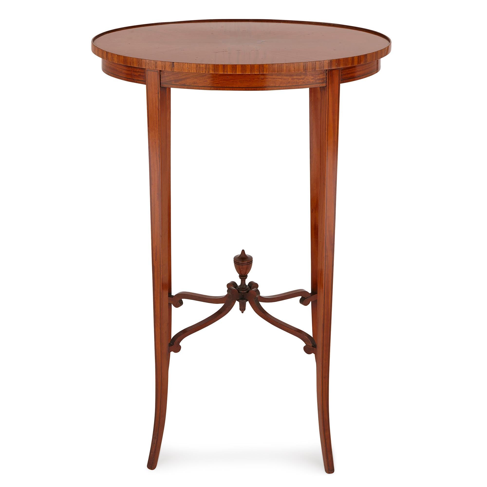 This table was created in England in the 19th century. It is crafted from satinwood, and is fitted with a mahogany stretcher. 

The table is comprised of an oval-shaped top, which features a parquetry design. The grain of the satinwood panels is