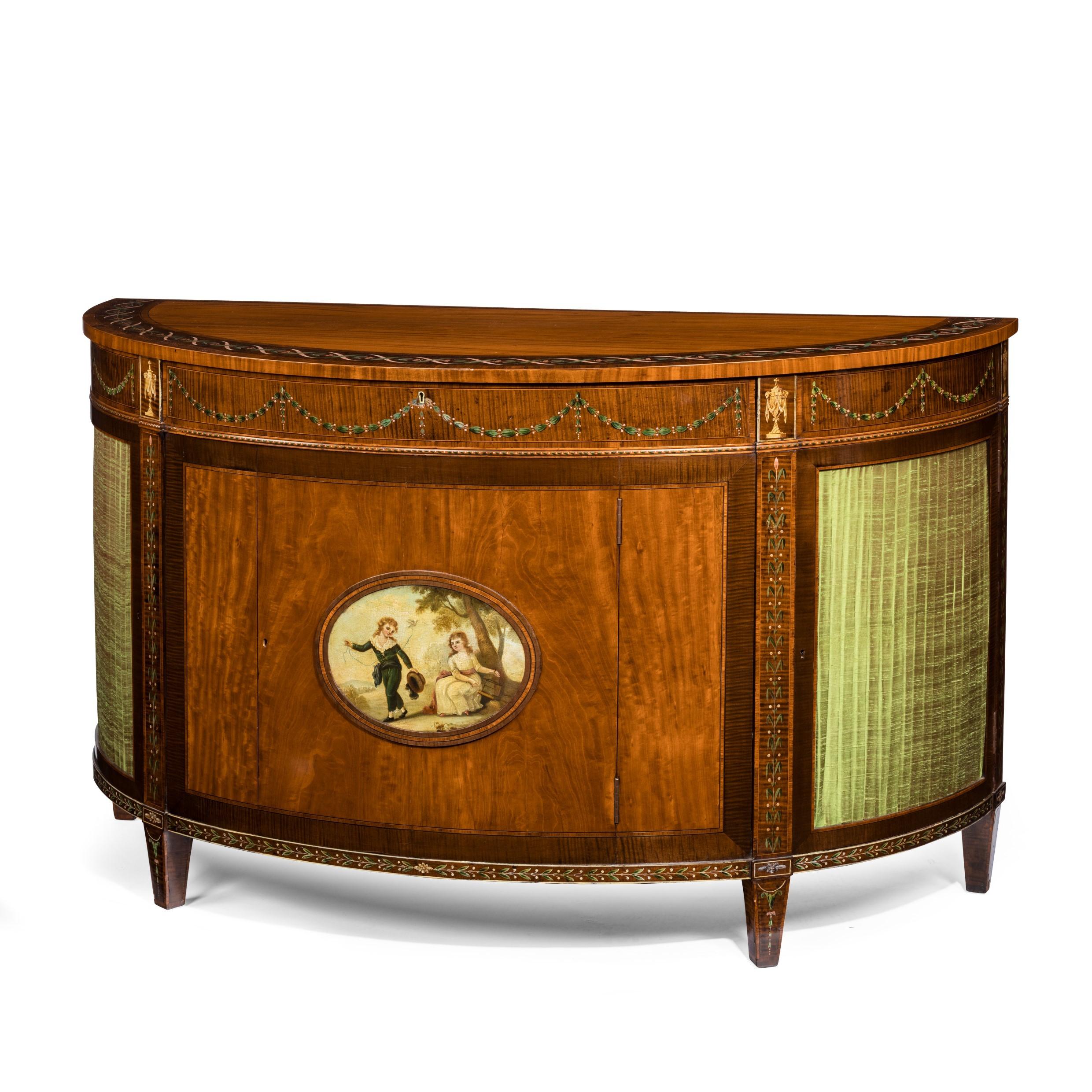 Victorian satinwood demi-lune commode in the Sheraton revival taste, with a central door showing a painted romantic scene between two panels of pleated silk, decorated throughout with delicate bands of flowers and bellflower swags in stained