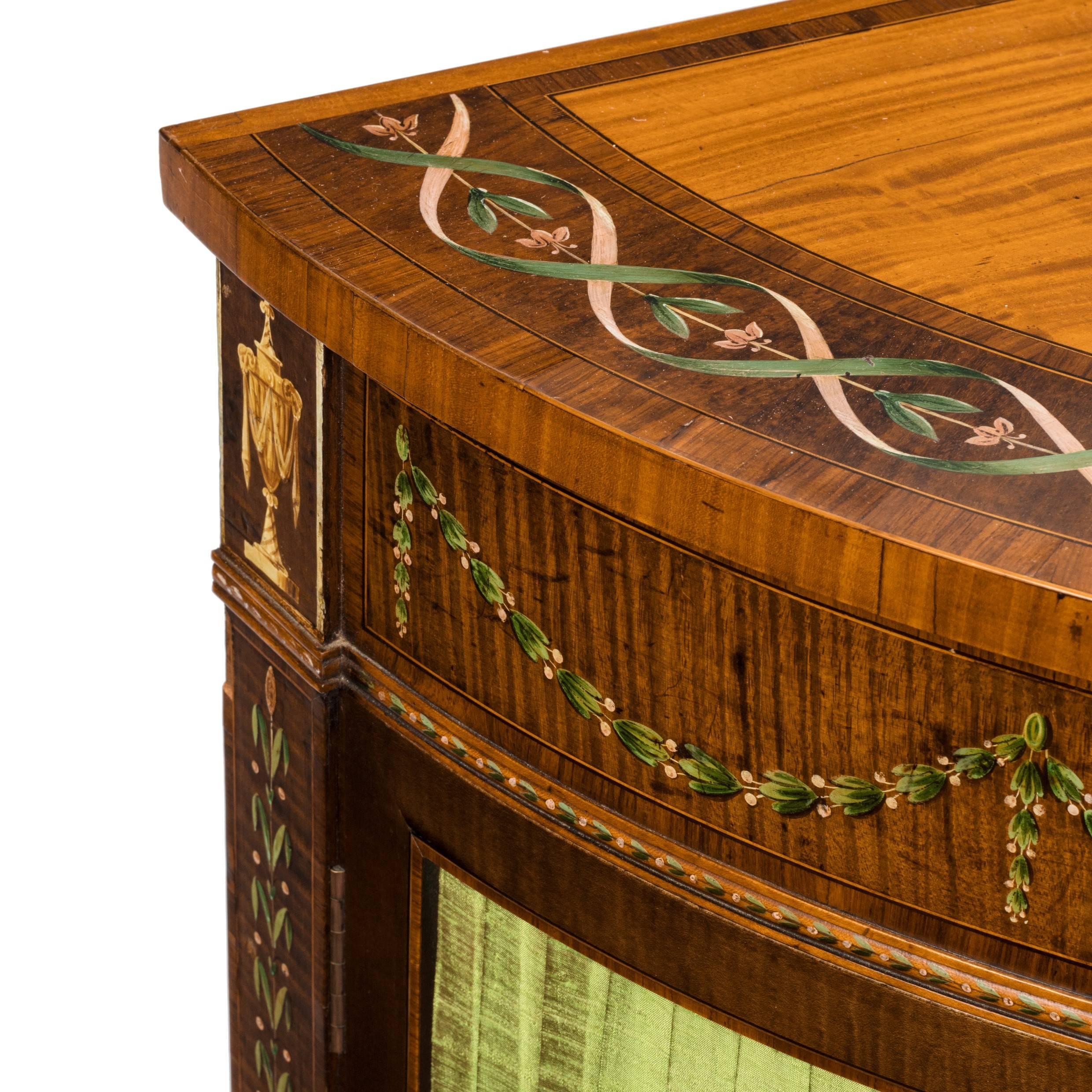 Victorian satinwood demilune commode in the Sheraton Revival taste, with a central door showing a painted romantic scene between two panels of pleated silk, decorated throughout with delicate bands of flowers and bellflower swags in stained boxwood.