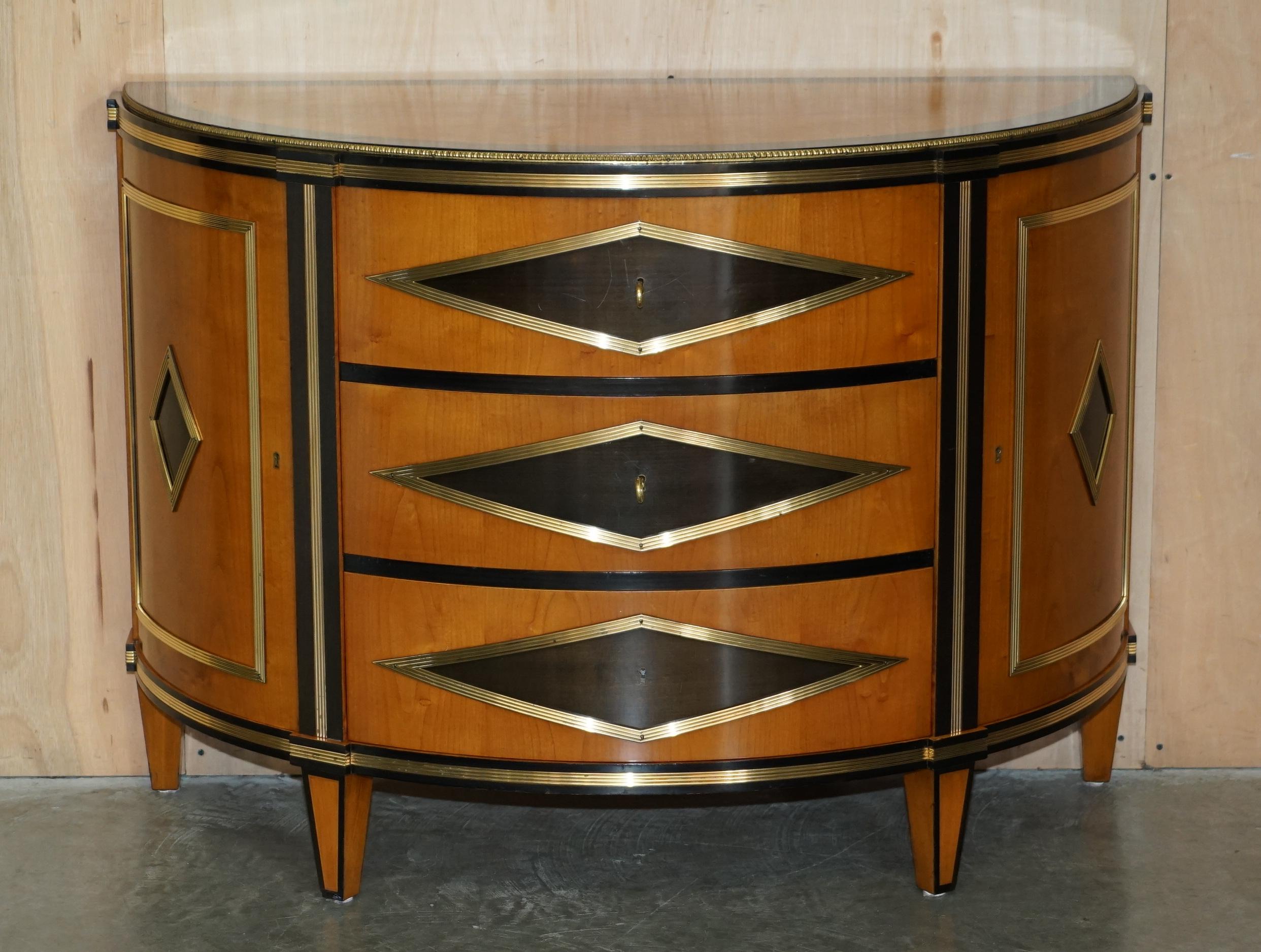 Royal House Antiques

Royal House Antiques is delighted to offer for sale these absolutely stunning, hand made in Italy Colombo Mobili Empire style Satinwood & gilt brass demi lune sideboard chest of drawers 

Please note the delivery fee listed is