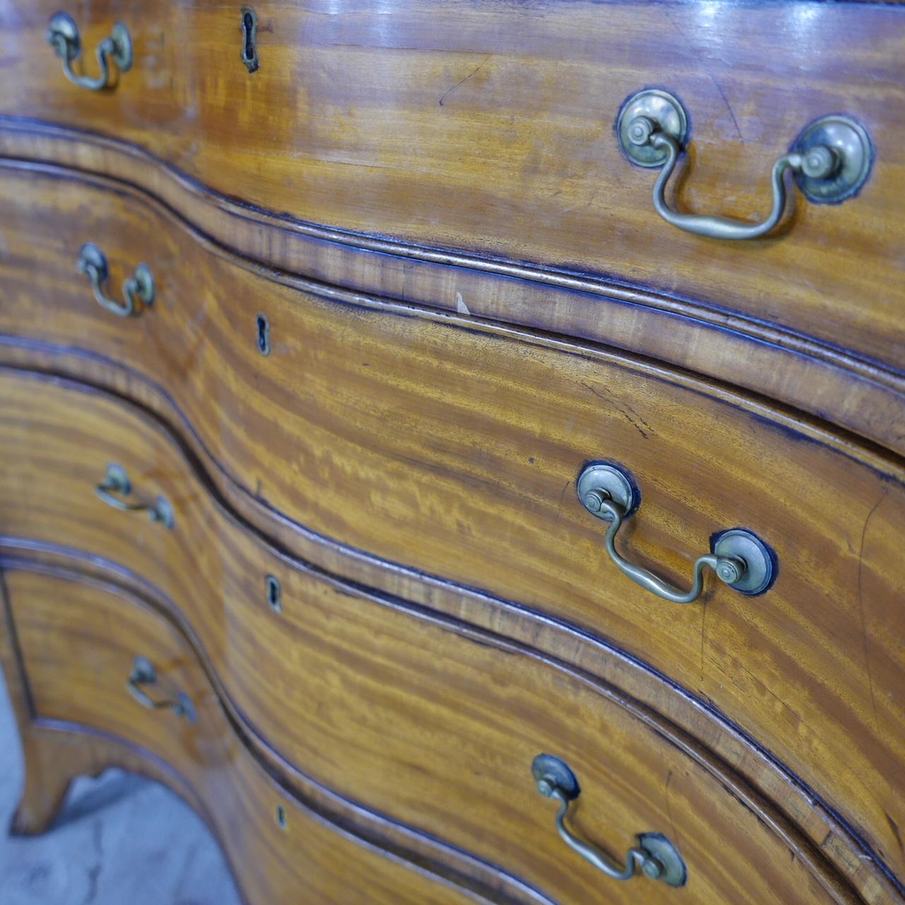 A satinwood serpentine chest in George III style, the crossbanded top above a baize lined brushing slide and four long graduated drawers.

Over bracket feet, late 19th / early 20th century, 

Provenance: The Collection of Sir Jeremy Lever.


