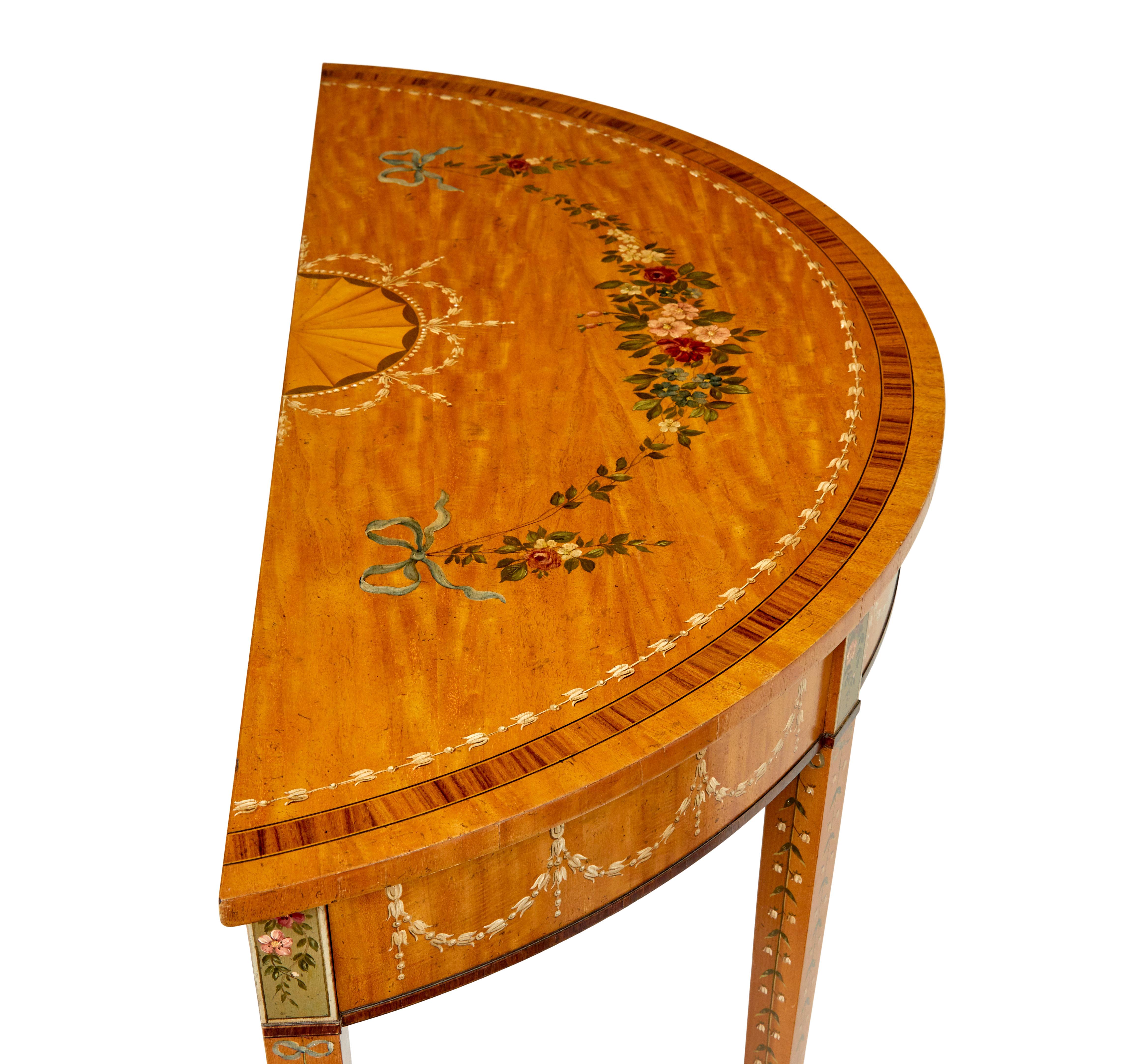 Satinwood hand painted demi lune table in the adams style circa 1990.

Here we have a good quality reproduction of a hand painted demi lune table in the adam's taste.

Satinwood demi lune top with cross banded and strung border.  Hand painted
