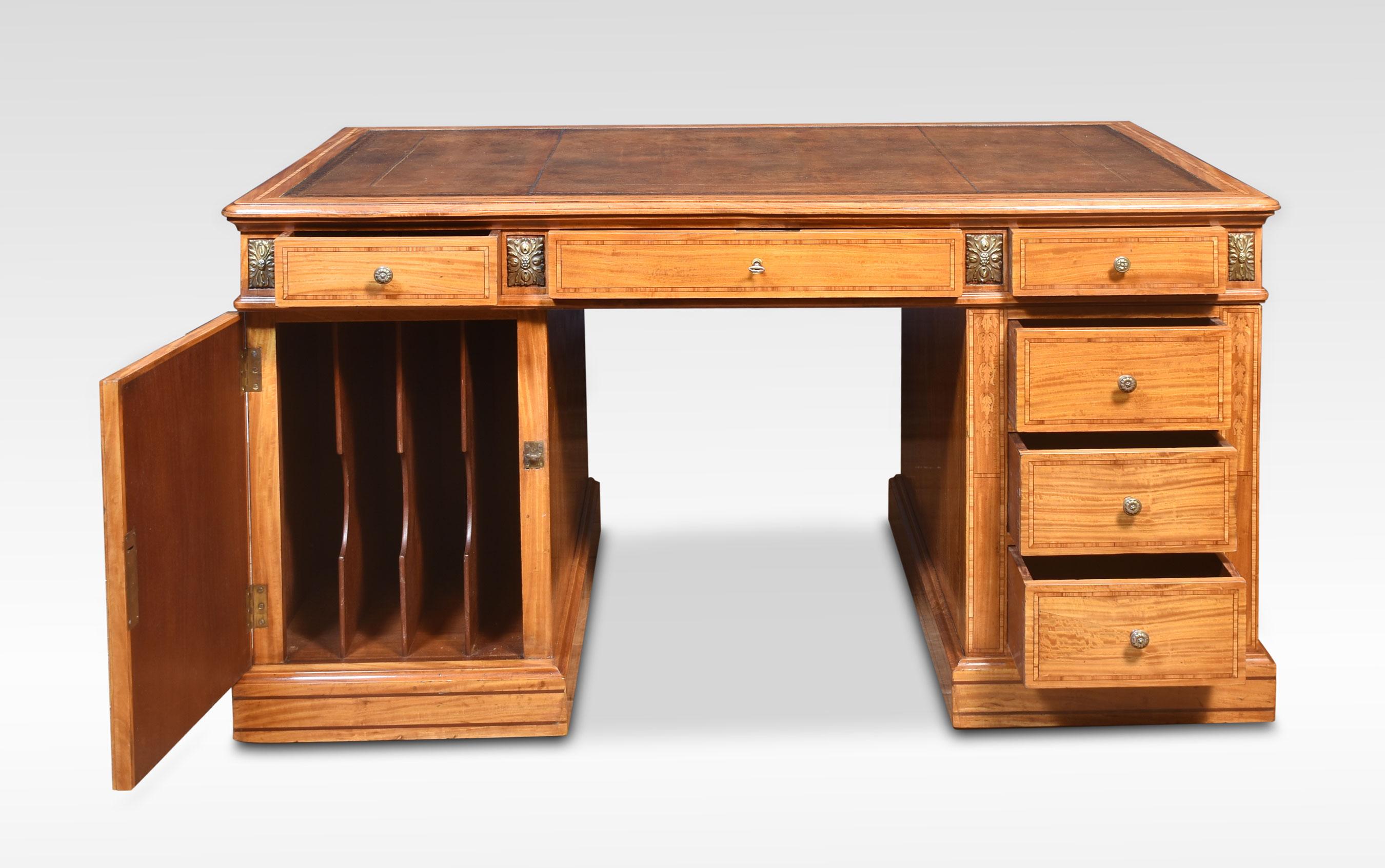 Satinwood partners desk, the large rectangular top with inset brown leather enclosed by tulipwood banding. To the frieze fitted with three drawers and twin pedestals below, one side with a bank of drawers, the other a panelled door enclosing