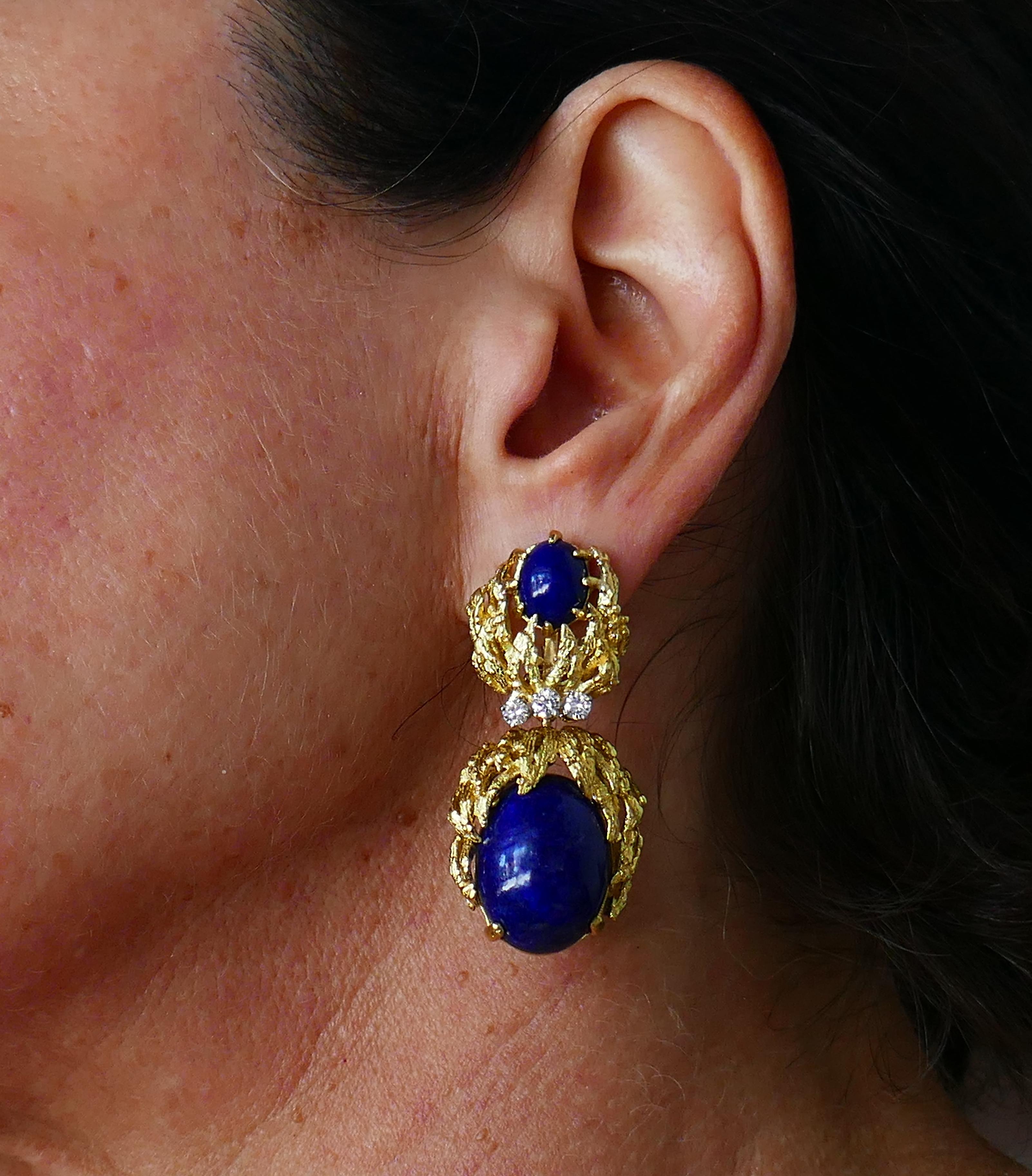 Colorful and prominent earrings created by Ruth Satsky in the 1950s. They feature oval cabochon lapis lazuli set in 18 karat yellow gold and accentuated with three diamonds (G-H color, VS clarity, total weight approximately 0.60 carat). 
The