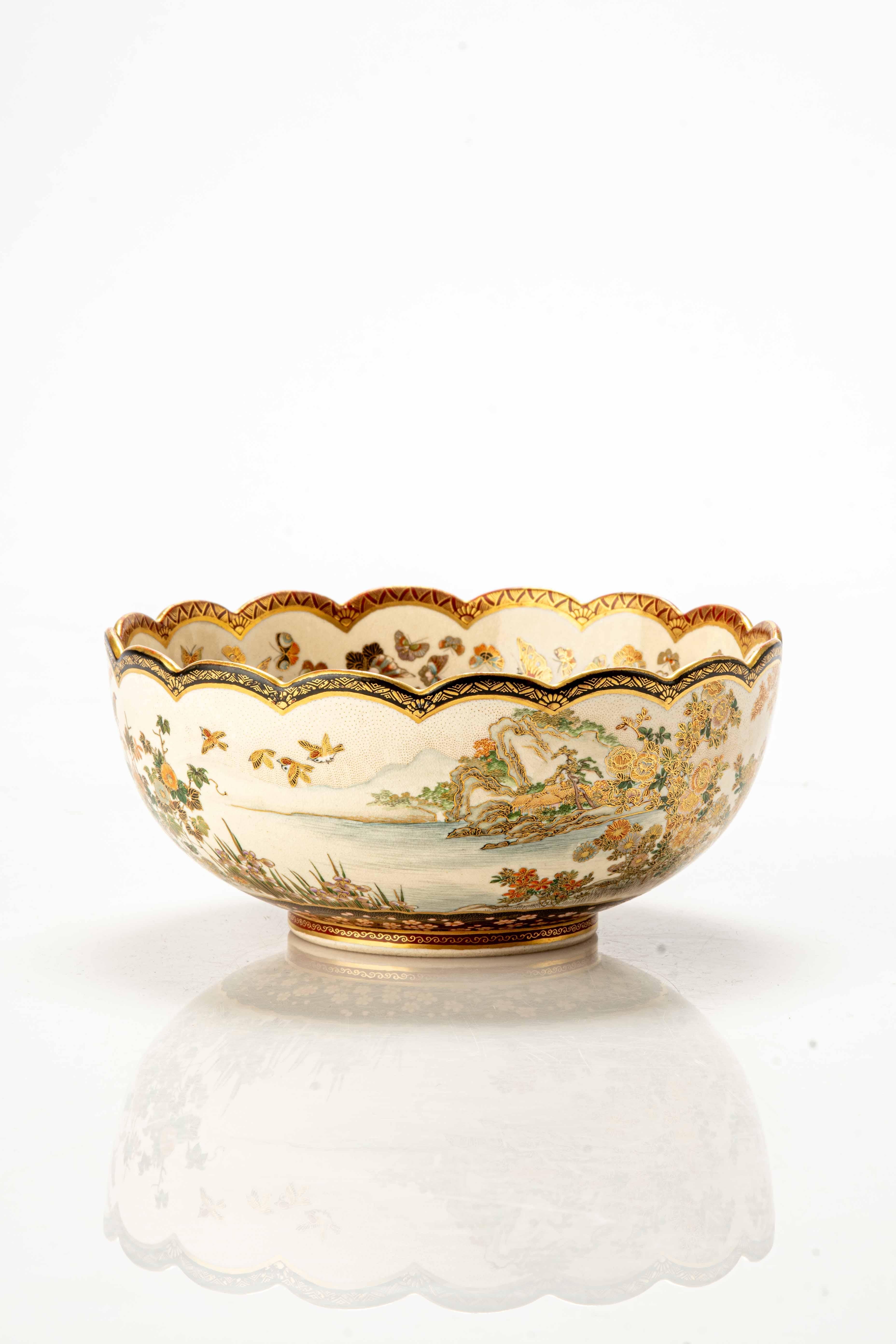 Satsuma ceramic lobed bowl adorned with raised enamels and fine gold details, depicting a vibrant landscape within. Characters and traditional Japanese homes emerge from the landscape while in the background, mountains and snow-capped Mount Fuji add