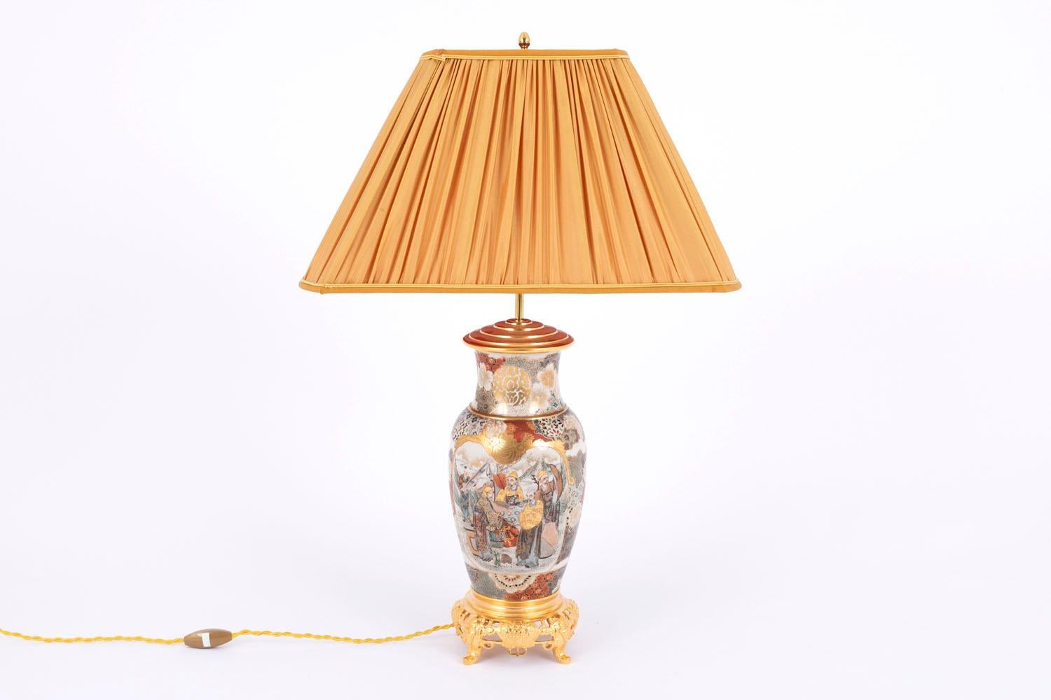 Satsuma earthenware lamp in baluster shape with polychrome enamels decoration on a white background mounted with chiselled and gilt bronze. Openwork decorated base standing on four small feet. 
Enameled decor on the body of the lamp with large