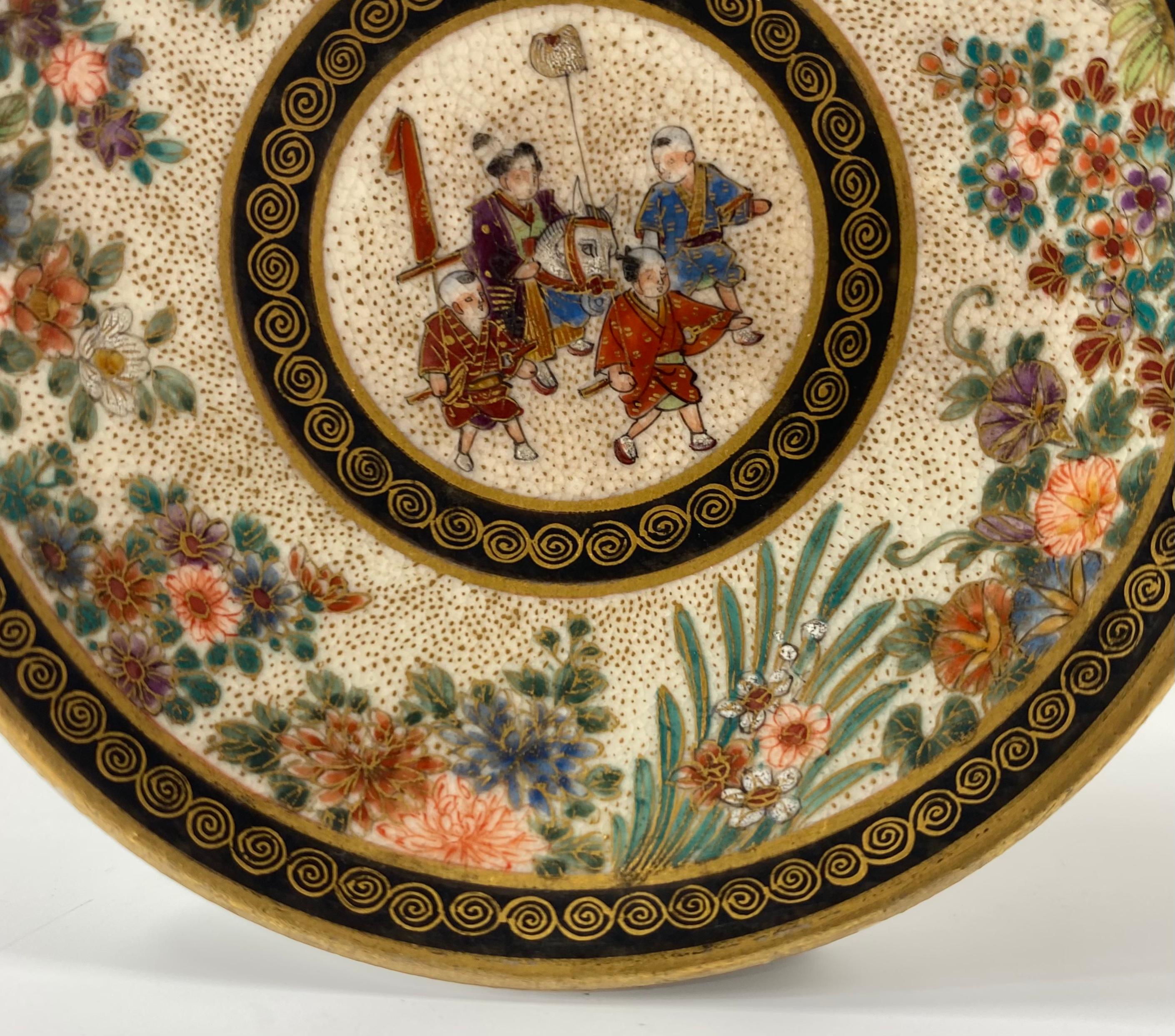 Satsuma pottery miniature dish, painted by Keizan, Meiji period. Hand painted to a central roundel, with a scene of boys in a procession, one riding a hobby horse.
The broad border painted with a continuous band of flowering plants, upon a gilt