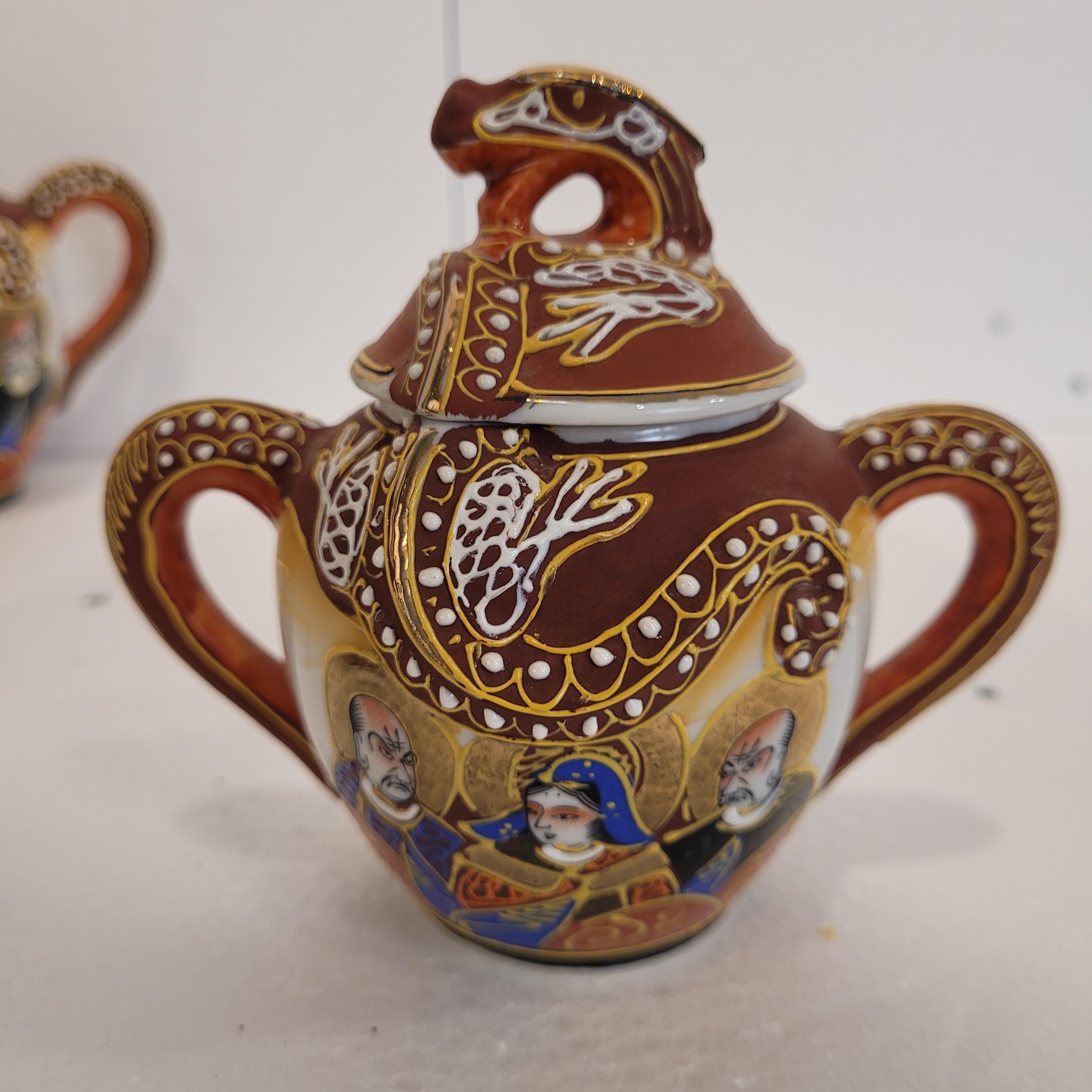 Gorgous and very Delicate six-piece tea or coffee set made of Japanese Satsuma porcelain. Cherry, blue, and ochre colors predominate. The main motif features the goddess Kannon surrounded by Buddhist monks. Goddess of compassion, venerated for her