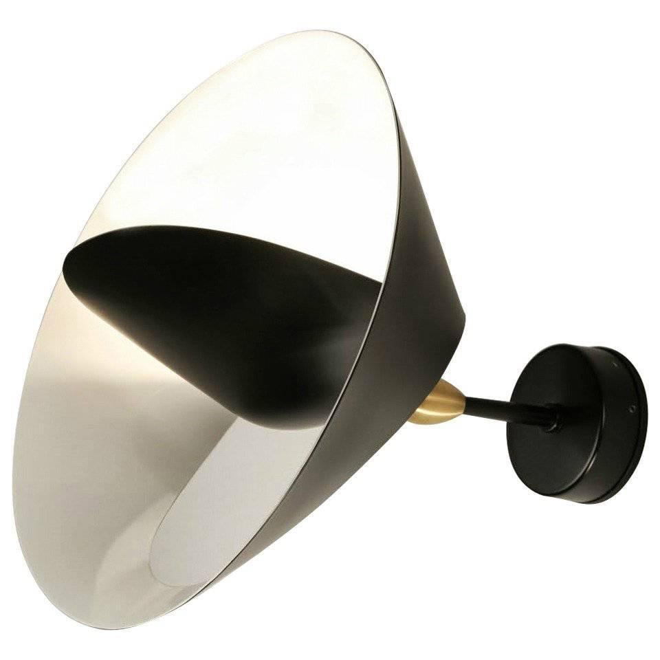 A partial cut allows the outer edge to bend revealing a sculpted ring encircling a central cone reflector to both diffuse and project light into the room. The result is reminiscent of a heavenly body.

Painted aluminum and steel with brass fixtures.