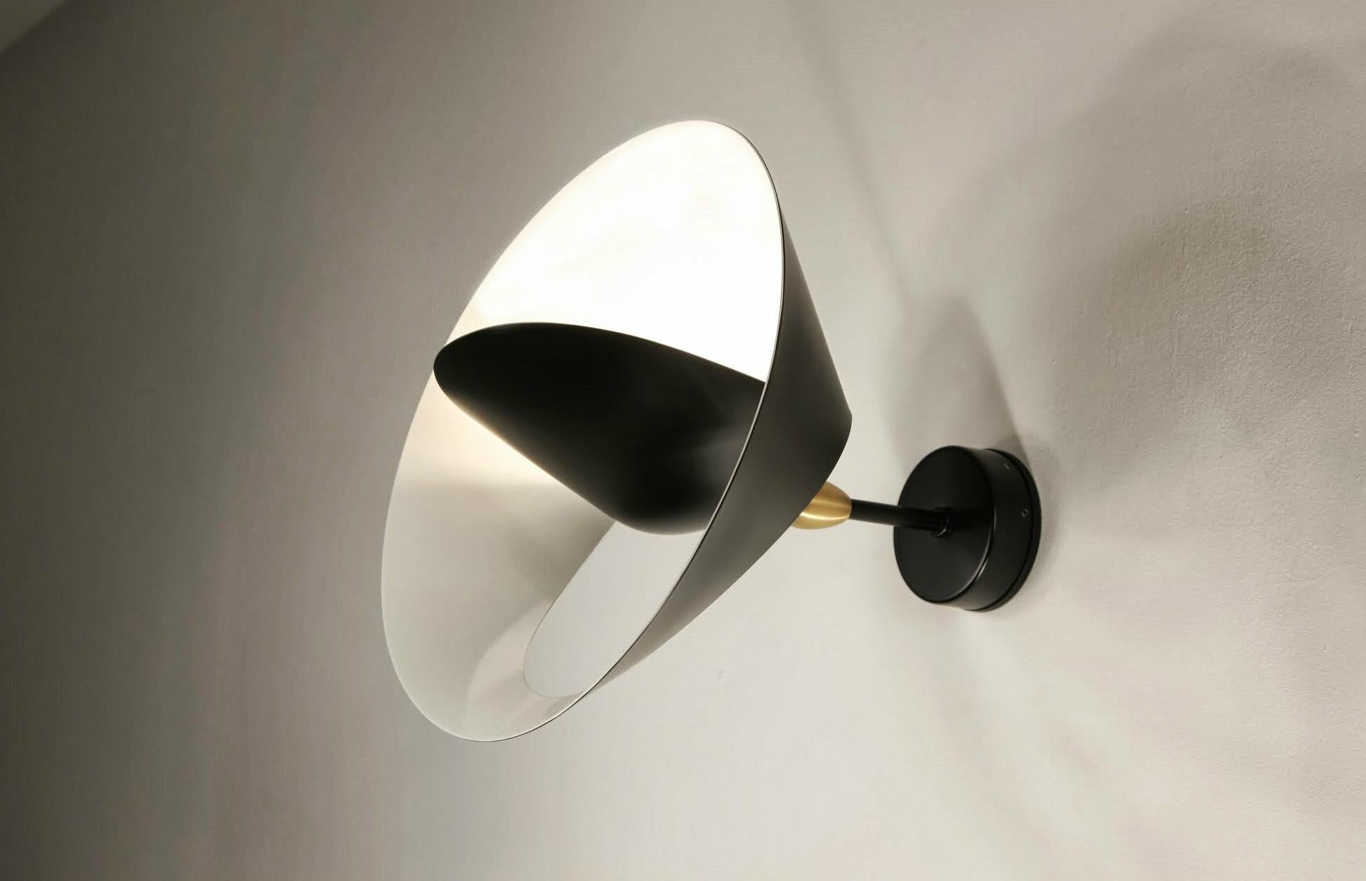 A partial cut allows the outer edge to bend revealing a sculpted ring encircling a central cone reflector to both diffuse and project light into the room. The result is reminiscent of a heavenly body.

Painted aluminum and steel with brass fixtures.