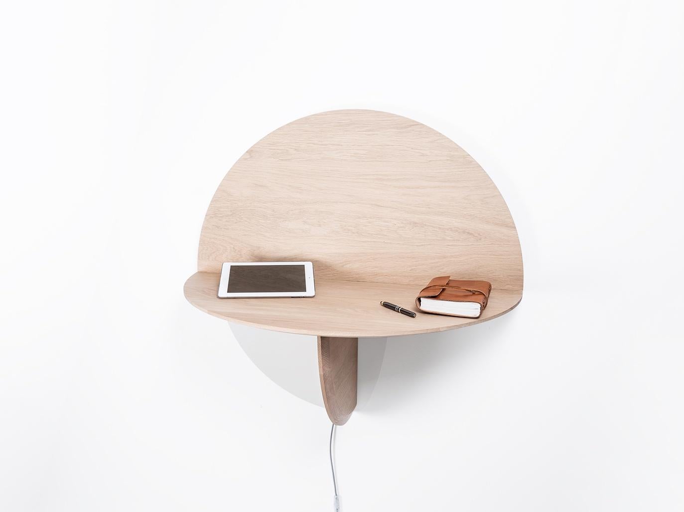 When Saturne becomes half-moon: with a beautiful decorative panel in oak, Saturne highlights the beauty of solid wood. The LED ribbon behind makes it an original wall lamp. Lifted in half-moon, it be-comes a writing desk, with space for a computer,