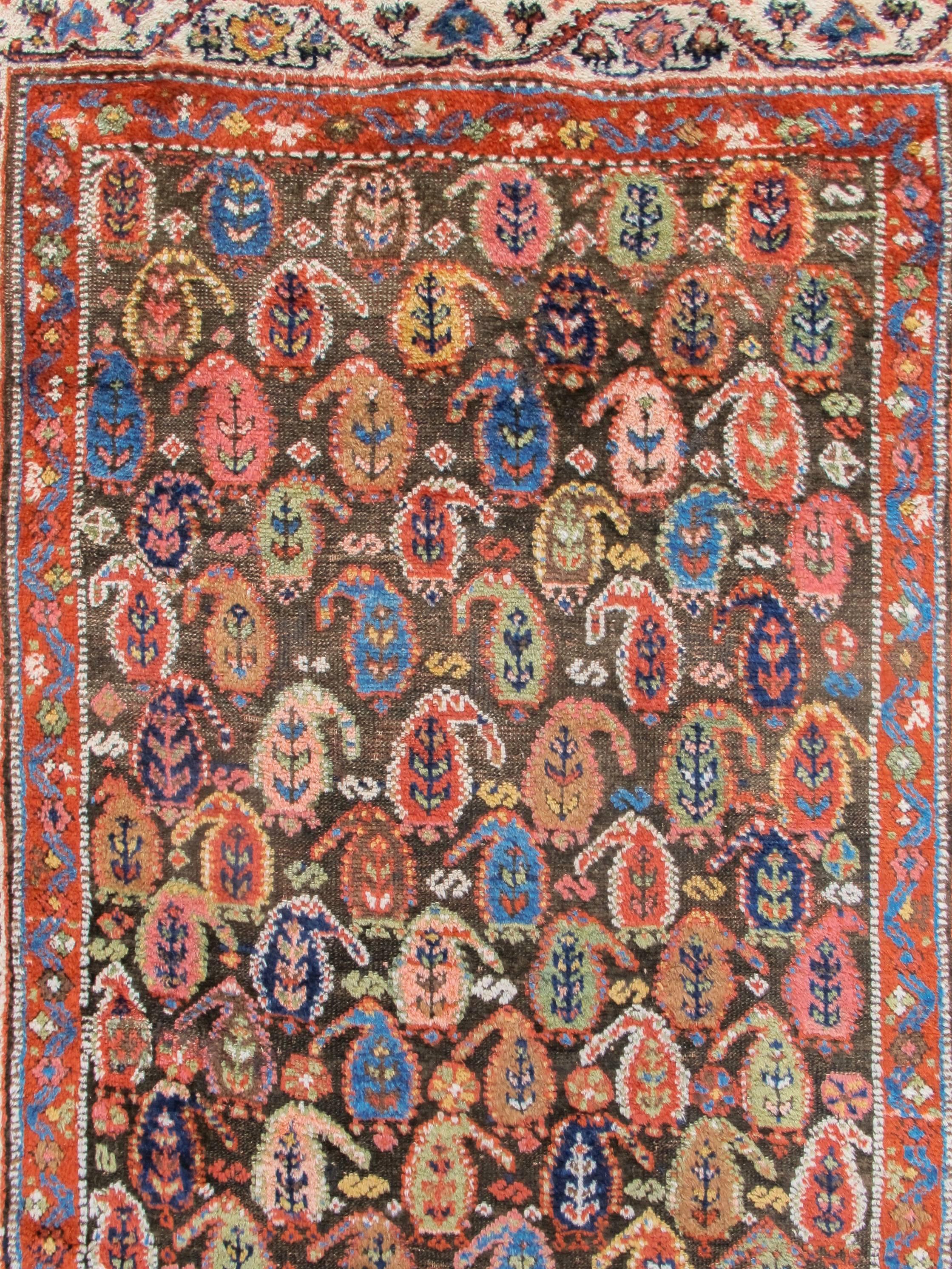 Rows of colorful 'boteh' paisley glisten against the deep chocolate ground of this Kurdish rug from Northwest Persia. Though refined and elegantly drawn, there is a definite sense of energy at work throughout the field as small variations in size,