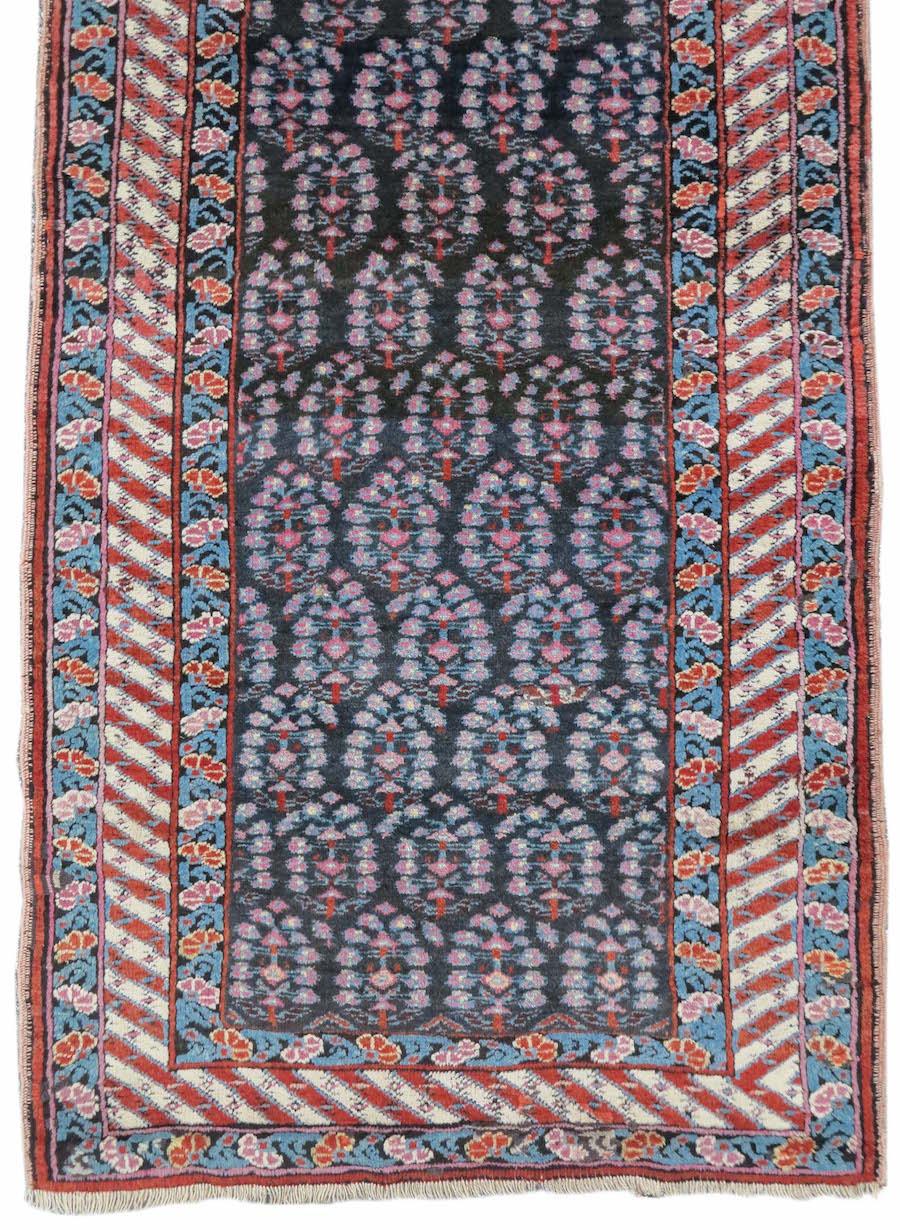 Antique Persian Sauj Bulagh Runner Rug, 19th Century

Against a deep indigo, almost black ground rows of ‘boteh’ paisleys are traced with lighter shades of green and violet across the field of this Northwest Persian runner. These open motifs are in