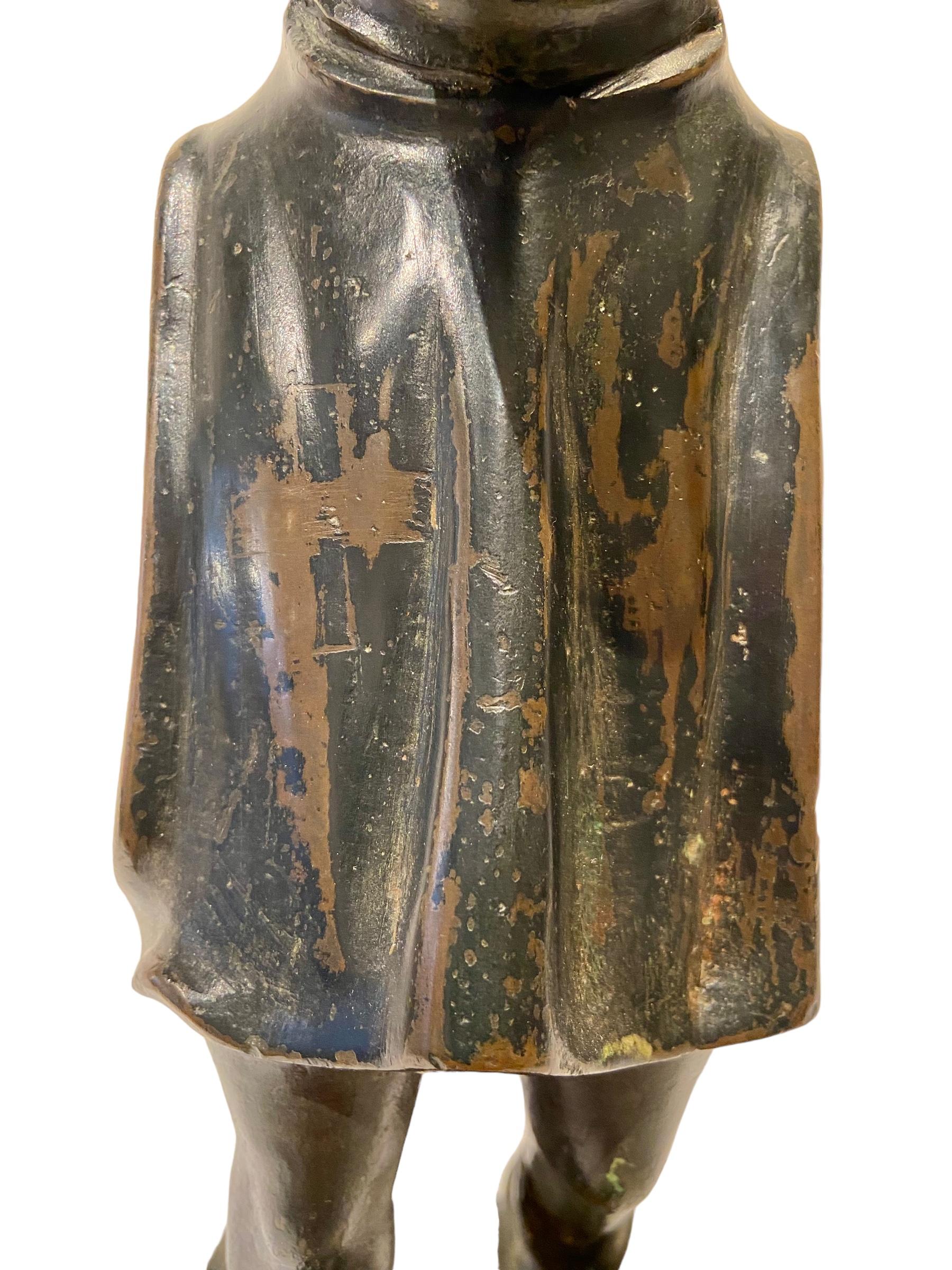 Eine wilde oder volkstümliche Figur aus Bronze auf einem Sockel aus Blaustein (neueren Datums).
Die Figur mit dem langen Spitzbart trägt einen Umhang mit Kapuze. 
Davor steht ein Kreuz. In seinen Händen hält er eine Keule. Wahrscheinlich