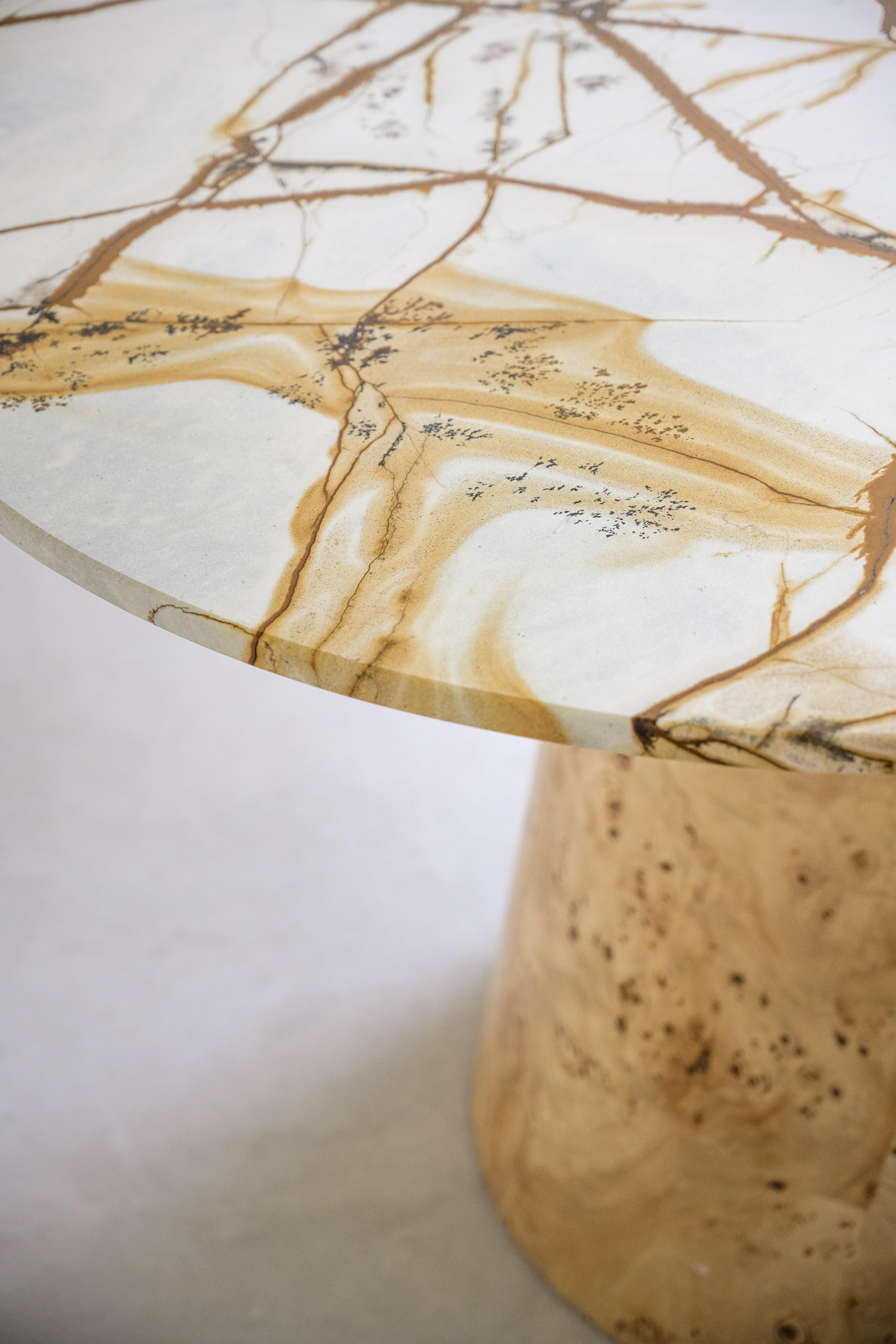 Der Tisch Savanna kombiniert eine Platte aus brasilianischem Quarzit mit auffälligen Goldmustern mit einem konischen Sockel aus strukturiertem Noppenholz - ein Design, das sowohl organische Eleganz als auch raffinierte Handwerkskunst widerspiegelt.