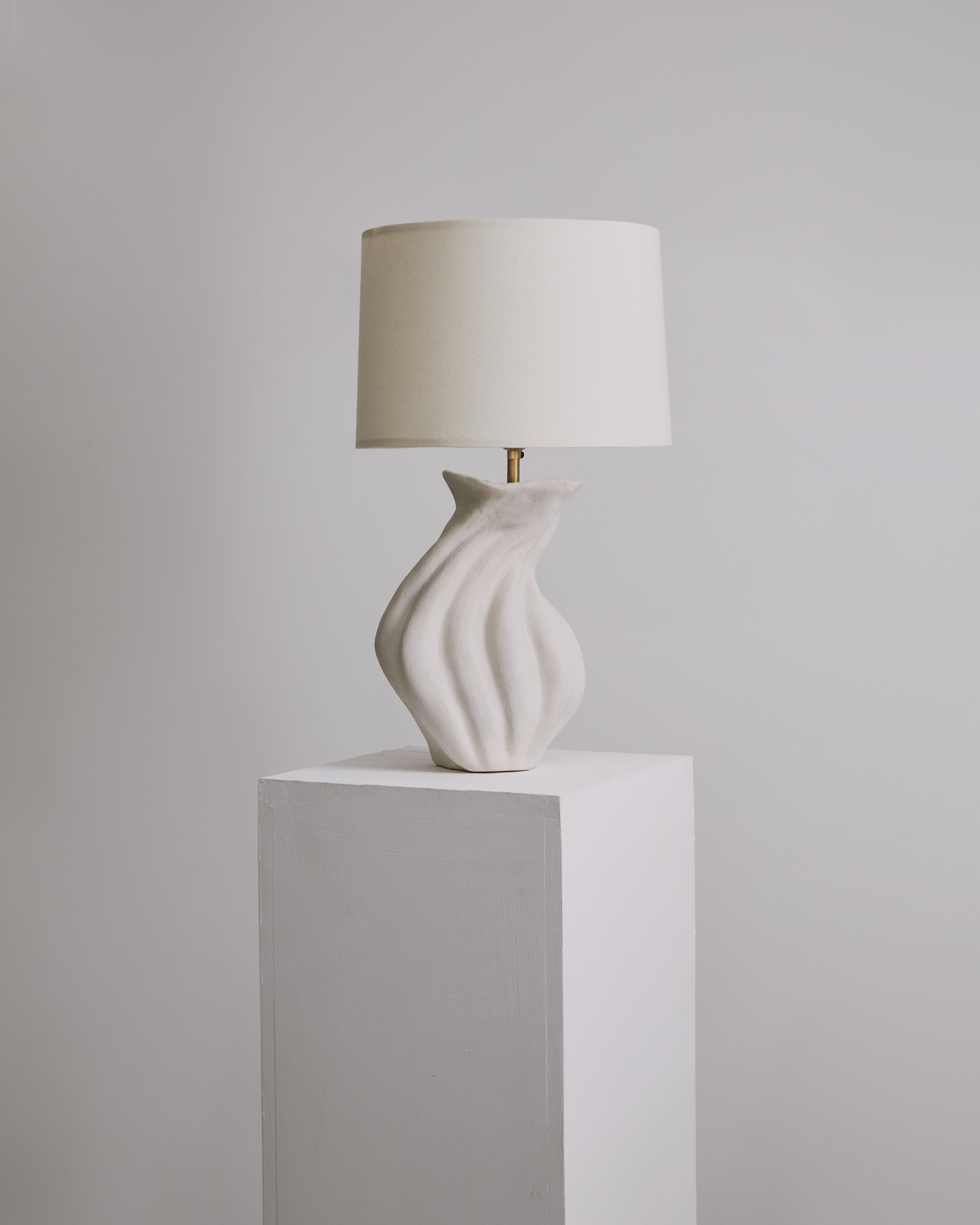 Lampe de table sculpturale en céramique Savin par Hanna Englund Ceramics. 
Dimensions : 30 x H 50 cm 
MATERIAL : Grès, céramique, laiton brut, lin. 
Choisissez entre l'abat-jour tissé blanc cassé et l'abat-jour tissé noir.
Fait partie de la série