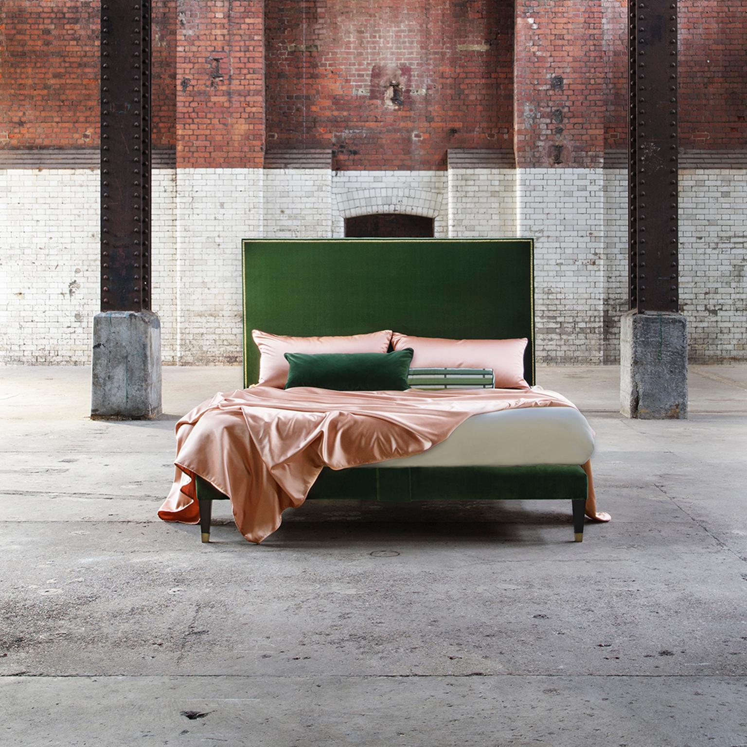 A Classic Savoir house design. The Harlech is a beautifully simple bed that adopts an angular, streamlined silhouette. The headboard and base are upholstered in a rich Hunter green velvet bordered with polished brass nailing. Finished with Georgian