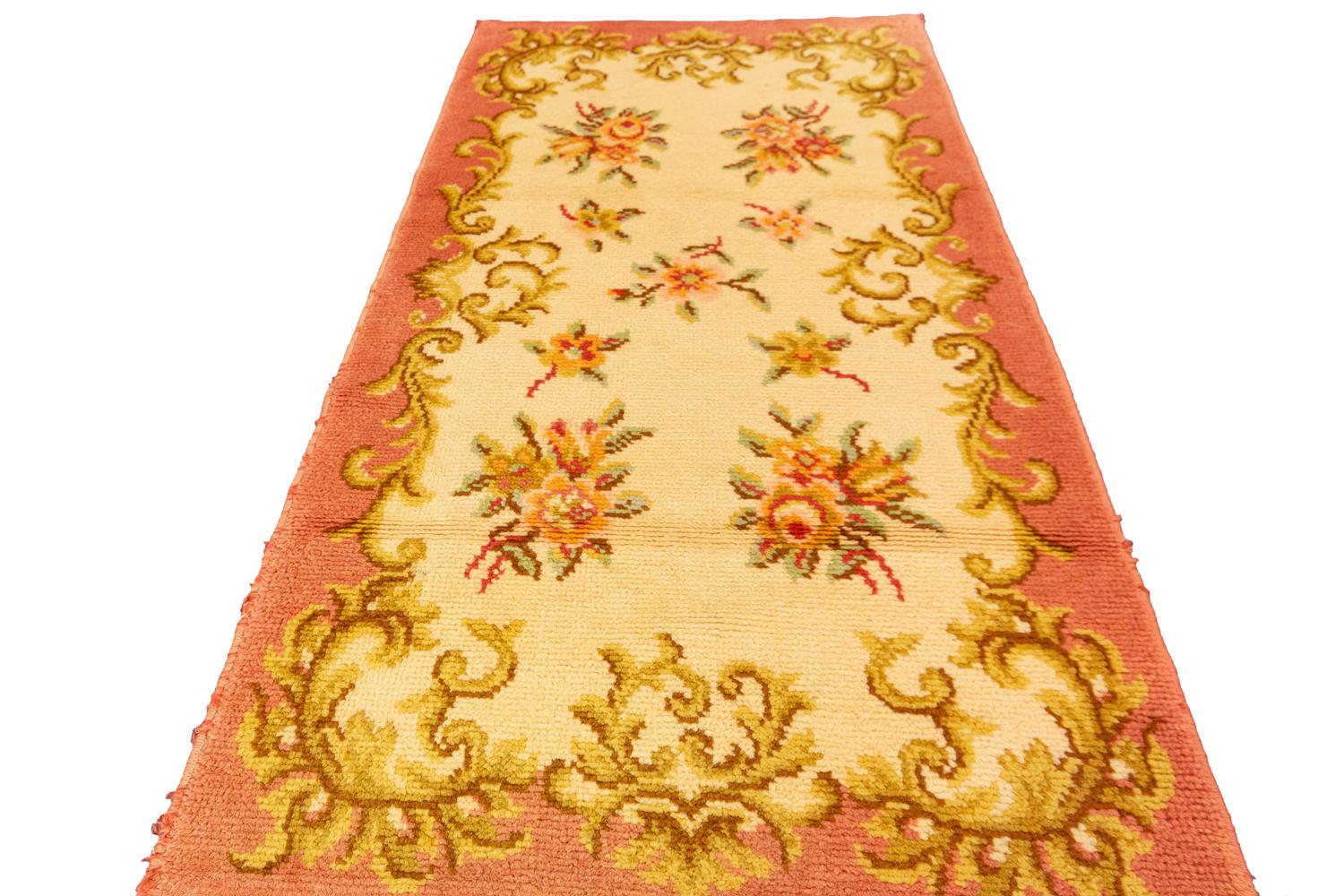 This is a vintage European rug woven during the second quarter of the 20th century circa 1920- 1950 and measures 141 x 72CM in size. It has a highly classical European drawing with golden-colored curling leaves which create a border and in close a