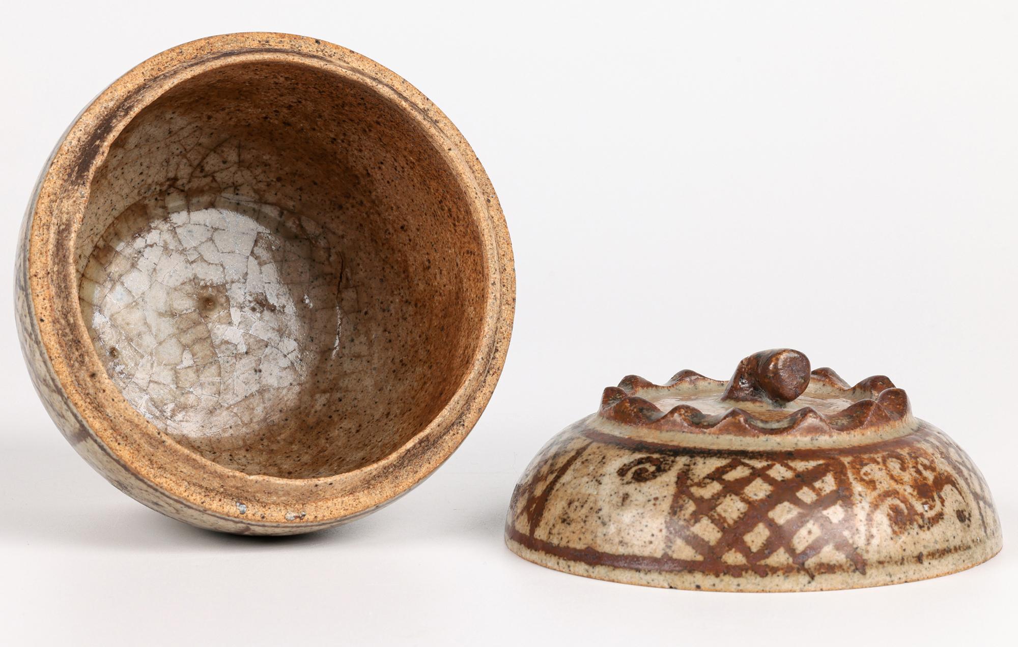 A delightful antique Sawankhalok Thai lidded vessel with hand painted patterning acquired as 15th century but believed later and probably 19th century. The finely and lightly potted vessel stands raised on a narrow round unglazed foot with a wide