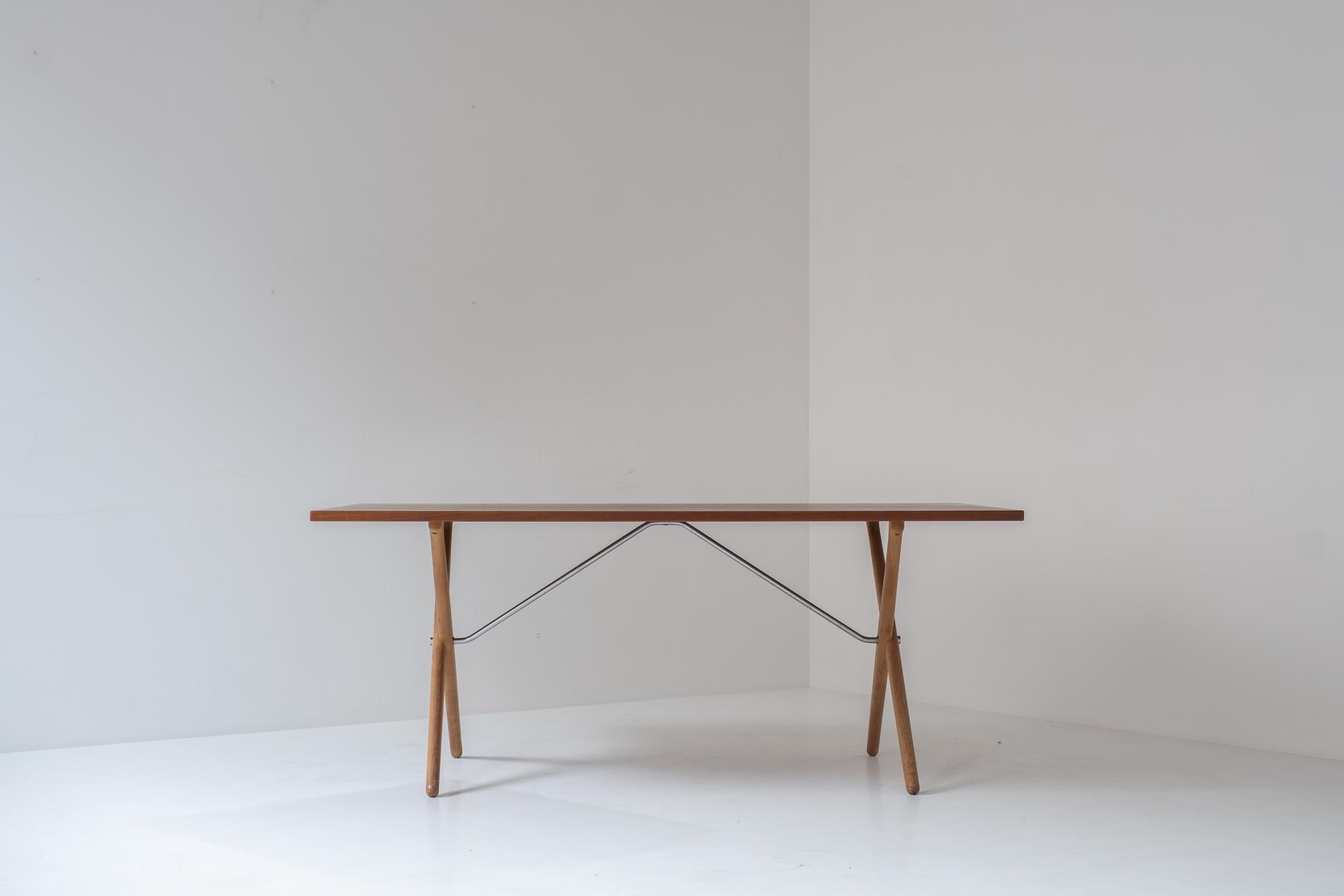 Early edition ‘Sawbuck’ or ‘AT 303’ dining table by Hans Wegner for Andreas Tuck, Denmark 1950’s. This cross-legged dining table features a top made out of teak, a frame made out of oak and a chrome support underneath. Presented in its original