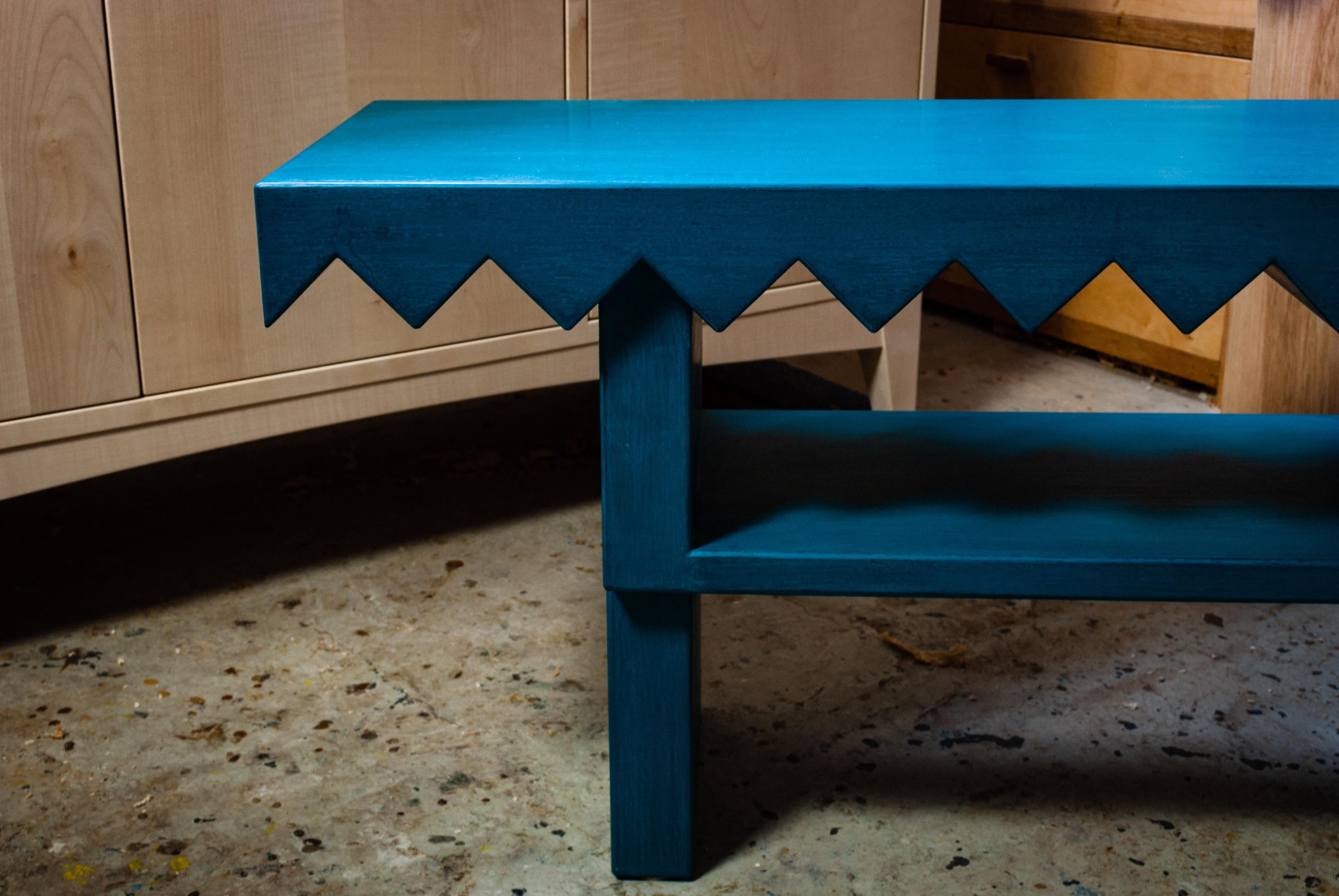 Solid English Oak bench with a simple, elegant and robust design.
Seats two people.
The solid seat has a playful sawtooth relief cut into it, and features precisely hand cut, wedged mortise and tenon joints. 

The bench is painted in a teal milk