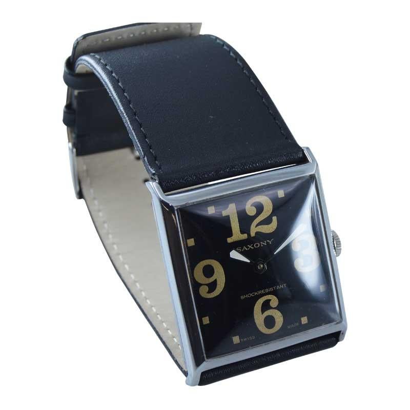 FABRIK / HAUS: Sächsische Uhrenfabrik
STIL / REFERENZ: Übergroße Uhr
METALL / MATERIAL: Nickel
CIRCA / JAHR: 1980er Jahre
ABMESSUNGEN / GRÖSSE: Länge 46mm x Breite 39mm
UHRWERK / KALIBER: Handaufzug 
ZIFFERN / ZEIGER: Original schwarzes Zifferblatt