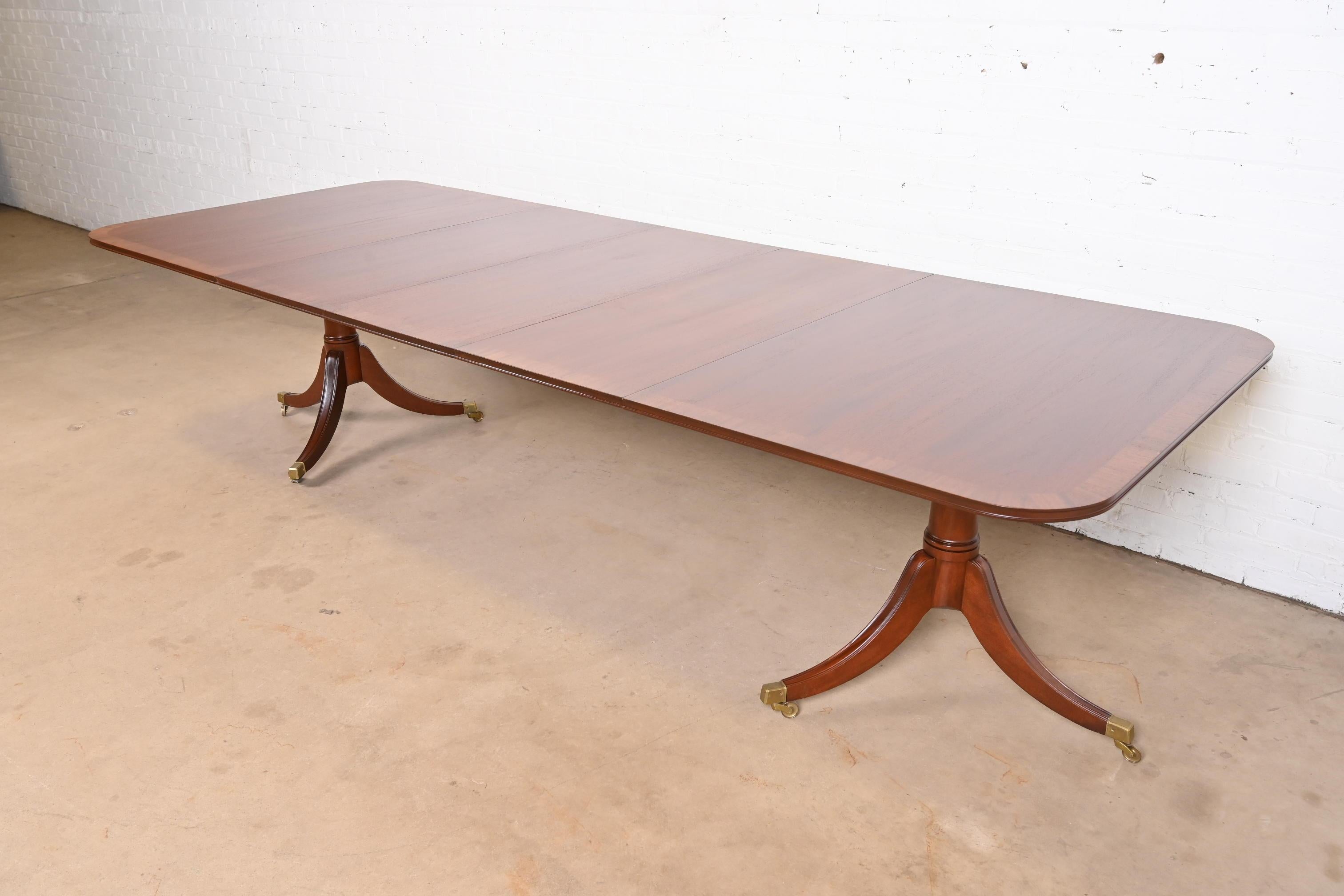 Magnifique table de salle à manger à double piédestal de style géorgien ou régence.

Par Saybolt Cleland

États-Unis, vers les années 1940

Magnifique acajou, avec bandes de bois satiné, piédestaux en acajou massif sculpté, et pieds coiffés de