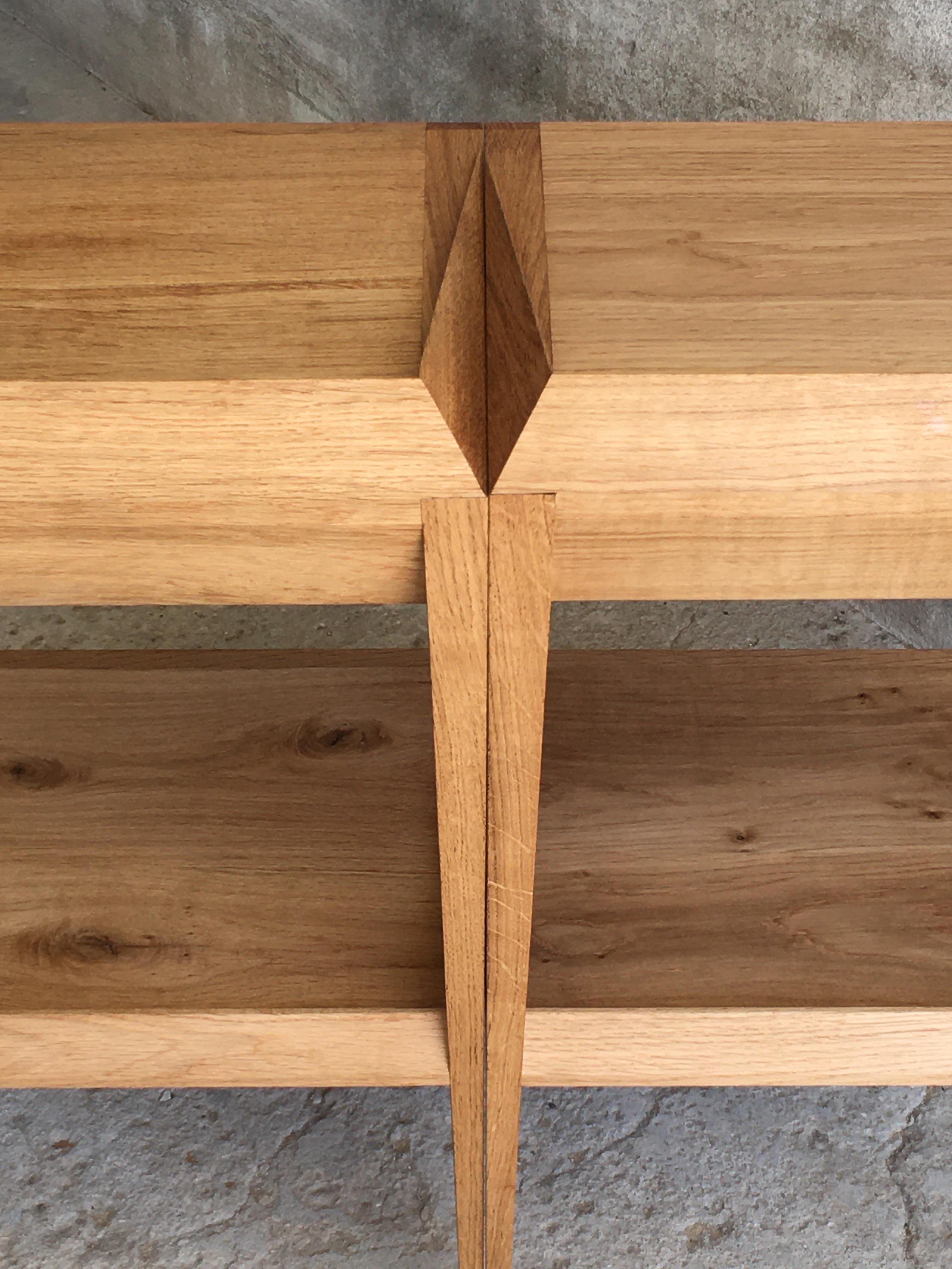 This carefully designed and handcrafted pair of bedside tables with very thin legs, designed and made by Tomaz Viana have a sculptural top part with a hidden small drawer. It´s geometrical shape,  feels modern but the fine woodwork keeps it