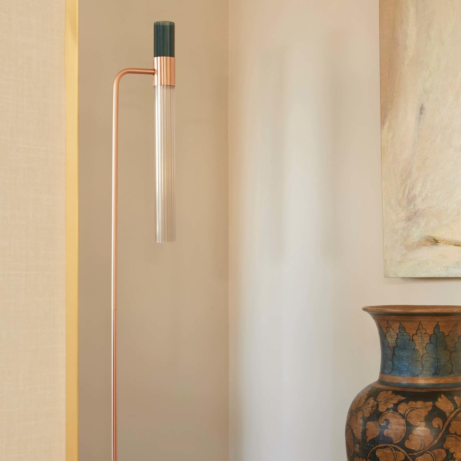 Bold and sophisticated, this floor lamp is a celebration of handmade craftsmanship and innovative technology. Its two grooved cylindrical shades, white and blue, rest on a pink champagne metal structure and are made by expert artisans of glass