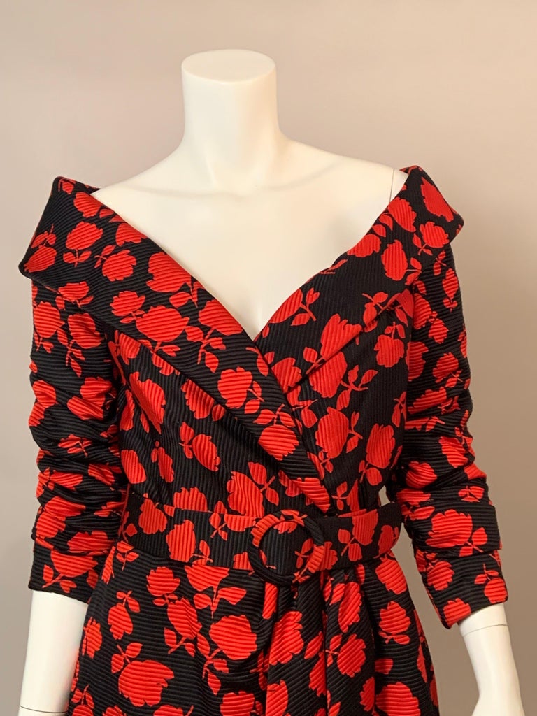 This charming Scaasi dress has a great pattern of red roses on a black silk faille dress.   The dress has a flattering off the shoulder neckline, gathered sleeves, a matching belt at the aide and a wrap style design.   There is a center back zipper