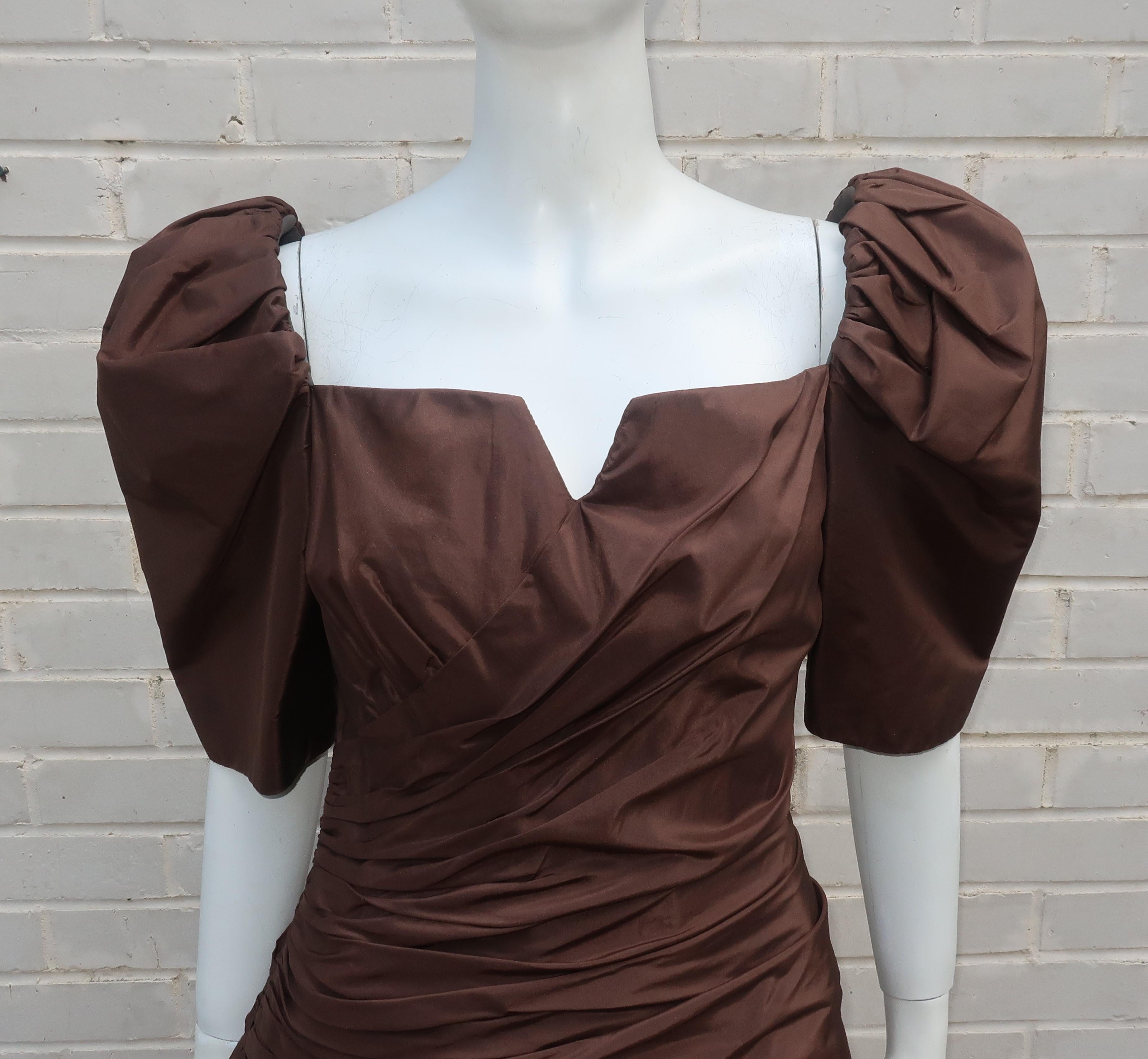 Gorgeous Arnold Scaasi brown silk taffeta cocktail dress with ruched torso and a dramatic neckline accented by puff sleeves.  The dress zips at the back side panel and is constructed with boning throughout the torso and at the top of the sleeves. 