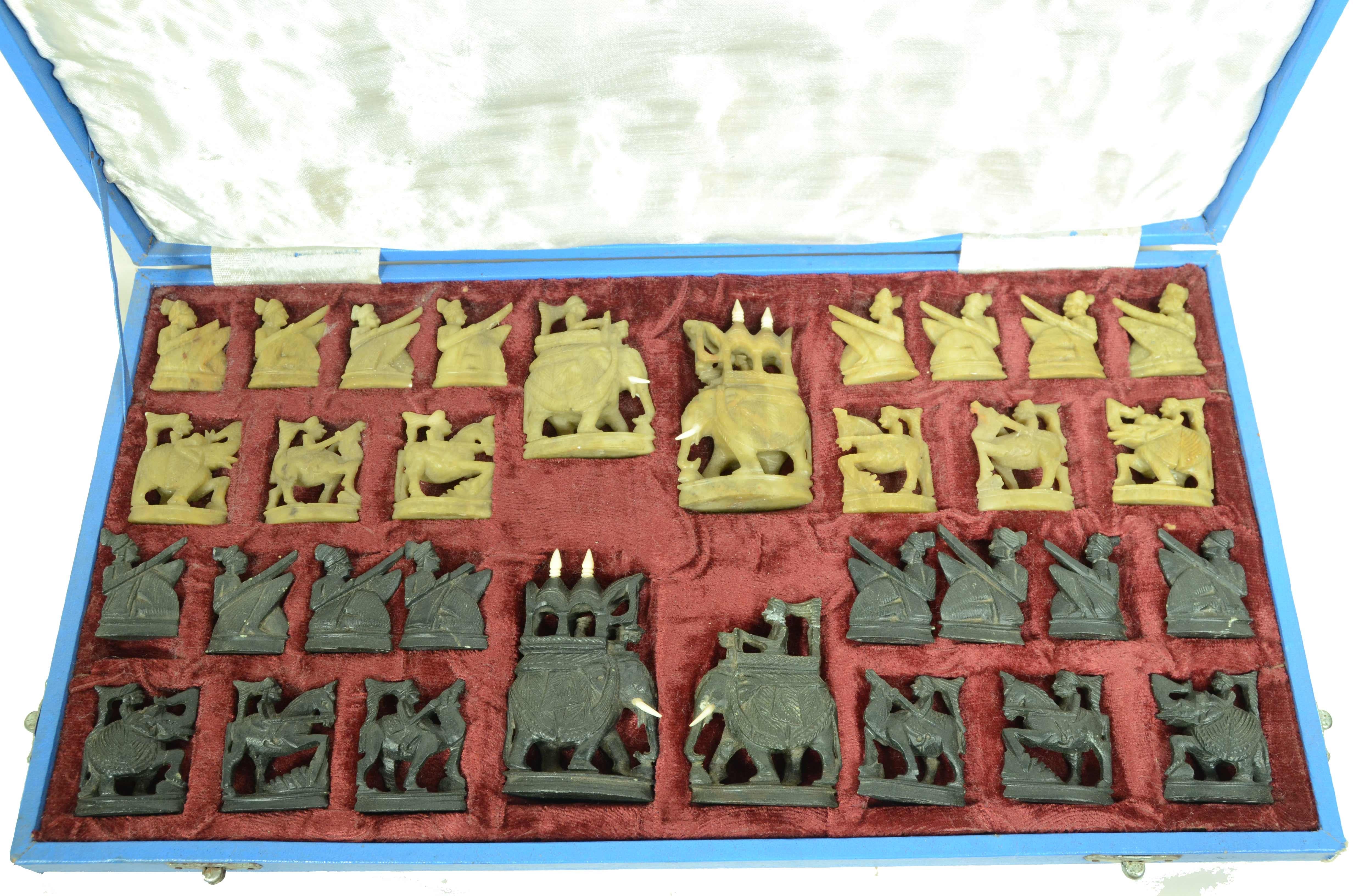 Indonesisches Schachbrett aus den 1950er Jahren aus Speckstein  geschnitzt, bestehend aus 32 Spielsteinen unterschiedlicher Größe in grün und schwarz. Die Steine sind in ihrer Originalschachtel untergebracht, die innen mit rotem Samt und weißem