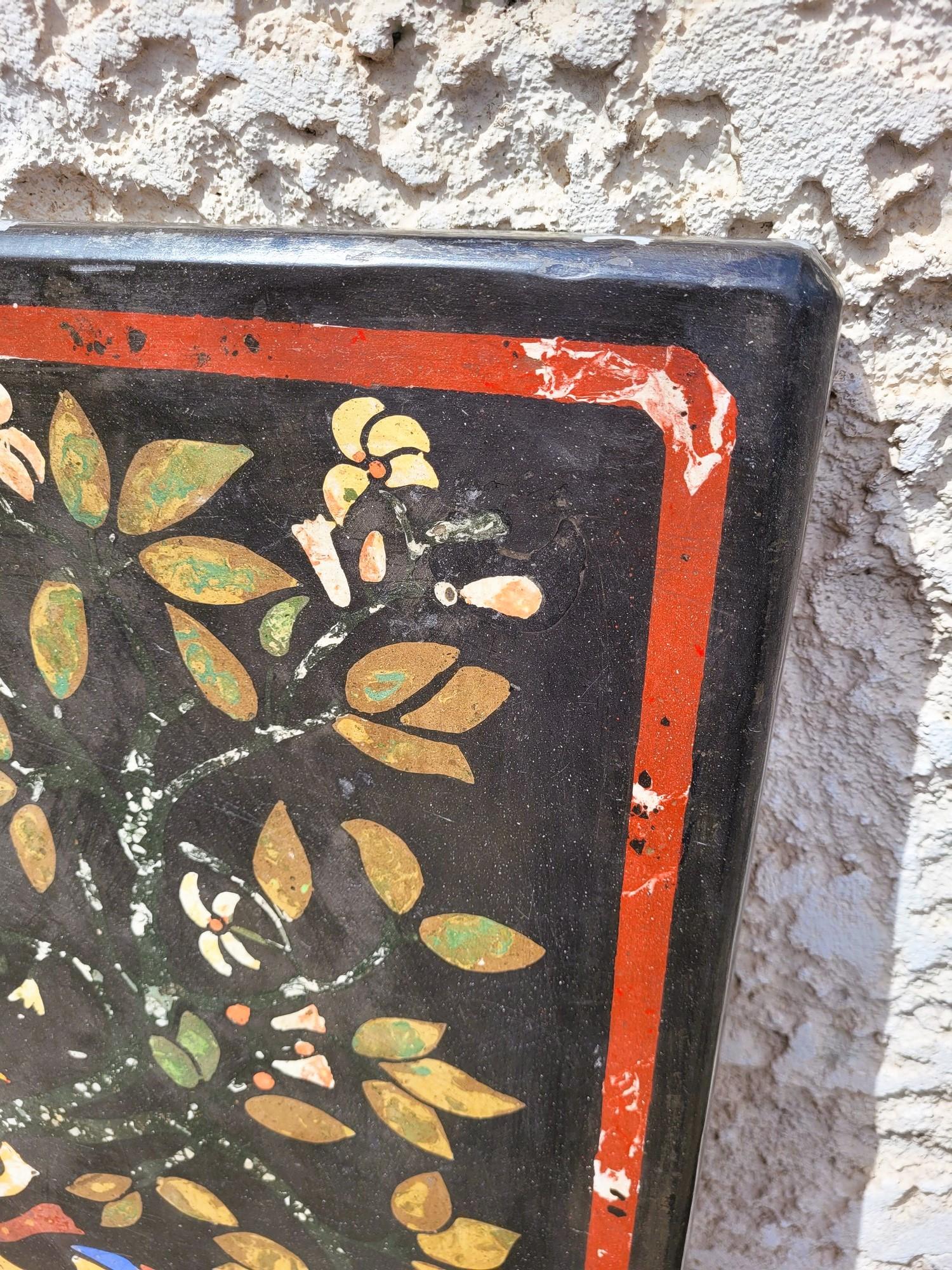 Panel Scagliola decorado con flores y hojas multicolores y un loro en el centro, sobre fondo negro

La técnica de Scagliola, ya conocida en la antigüedad, consiste principalmente en fabricar bandejas imitando mármol o marquetería de mármol.
También