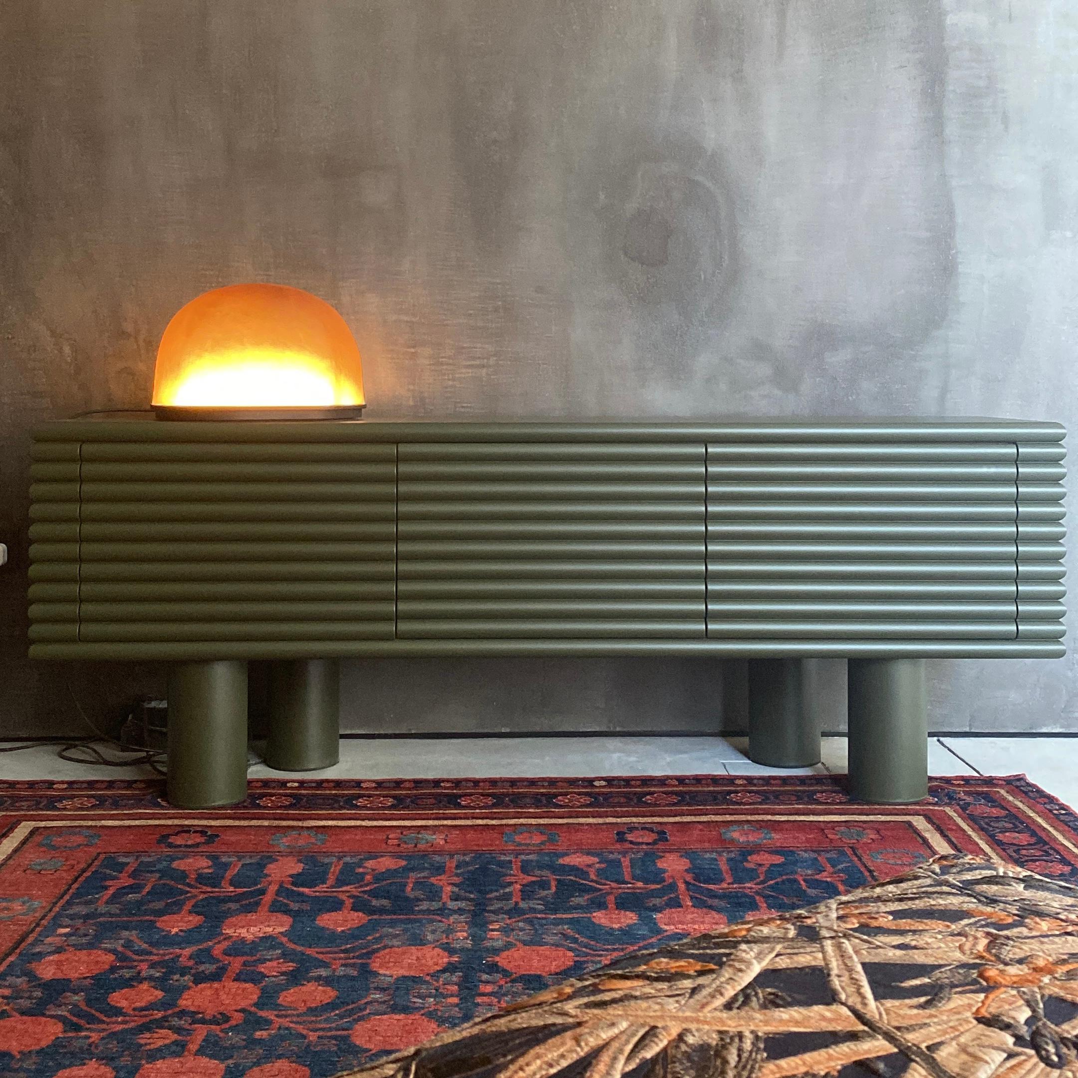 Le buffet Scala, conçu par Stéphane Parmentier, est un meuble élégant et distinctif à trois portes, recouvert de cuir de veau Golf imprimé gris clair et reposant sur une base à quatre pieds. Son design distinctif s'inspire de la forme 