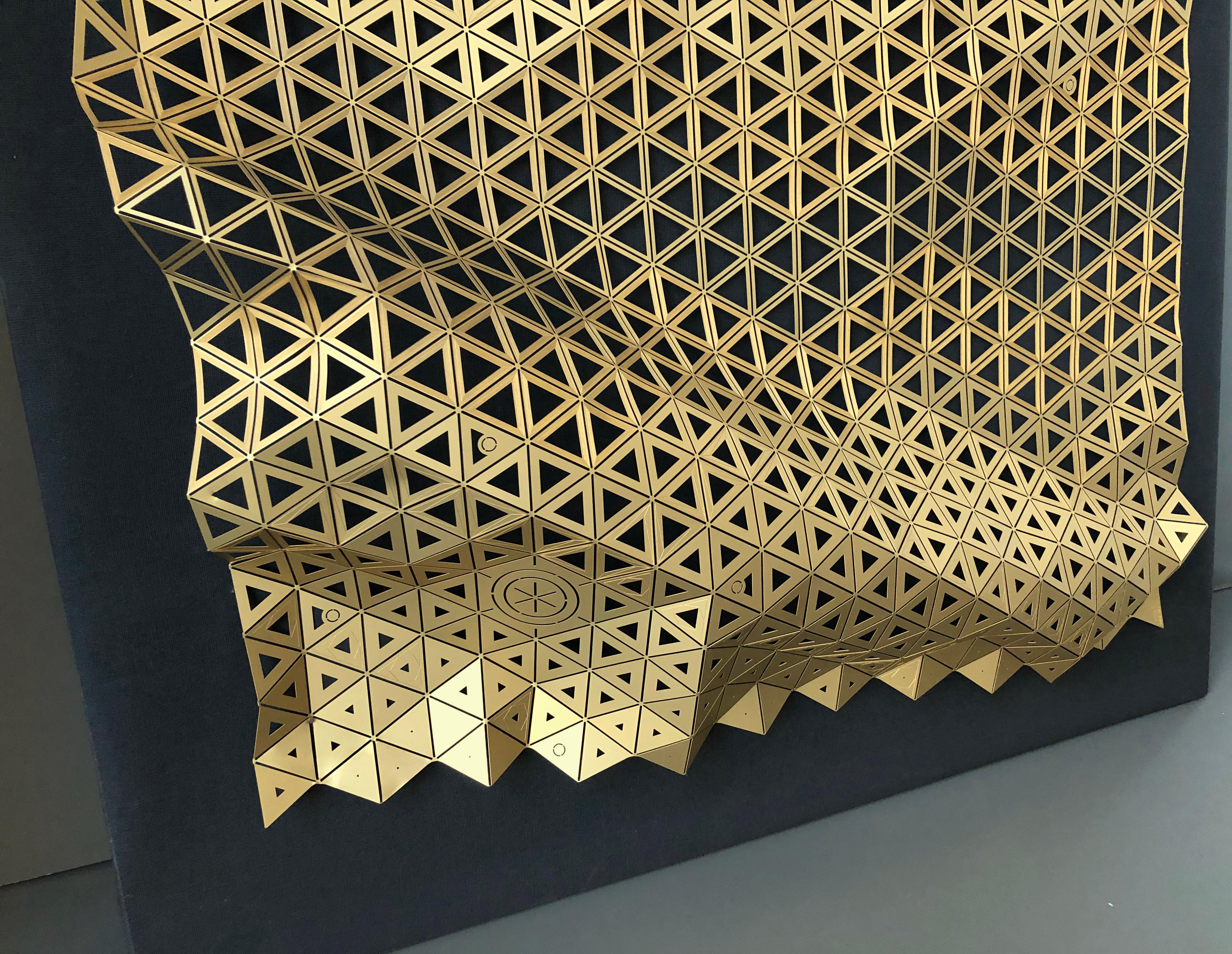 Une très fine feuille de laiton, finement gravée et découpée de motifs géométriques, se transforme en une surface tridimensionnelle capable d'enrichir les pièces par des jeux de lumière et de reflets raffinés. L'utilisation de technologies de pointe