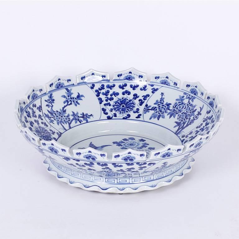 Blue and white Chinese export style footed bowl with an unusual scalloped or turret lip, hand decorated with alternating floral panels and a round centre panel with birds and flowers.