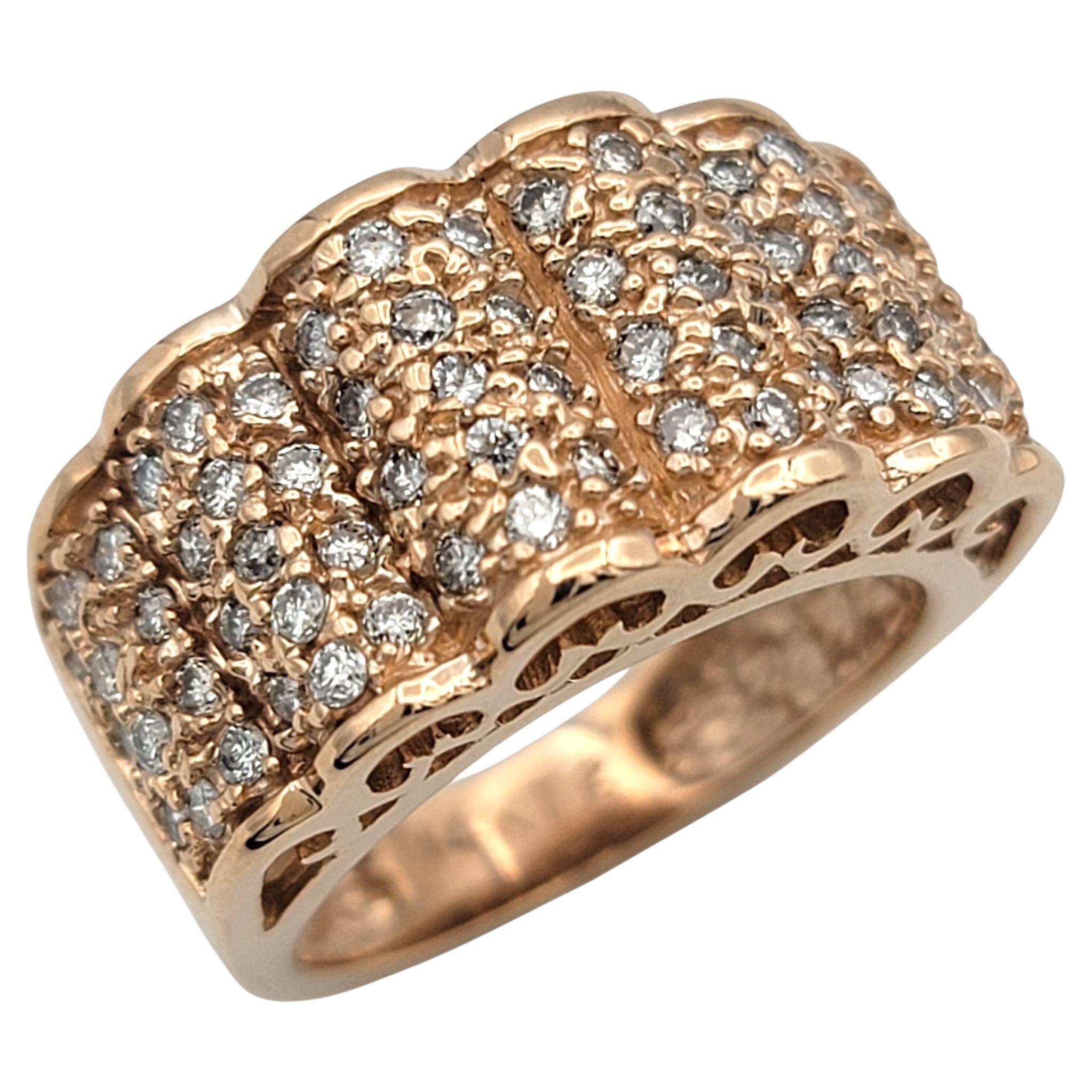 This 14 karat rose gold ring is designed with a bold, sculptural presence. The wide band features raised rows, each pavé set with brilliant round diamonds that create a continuous shimmer across the surface. Scalloped edges bring a touch of softness