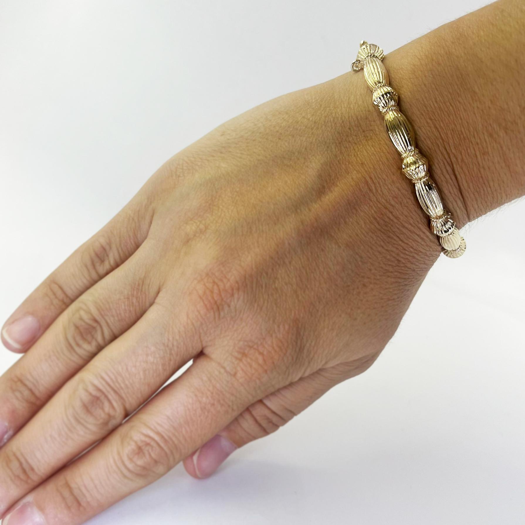 Bracelet à charnière ovale en or jaune 14 carats présentant un motif strié et festonné. Convient à un poignet jusqu'à 6,5 pouces. Fermoir caché avec chaîne de sécurité. Le poids fini est de 20,4 grammes.