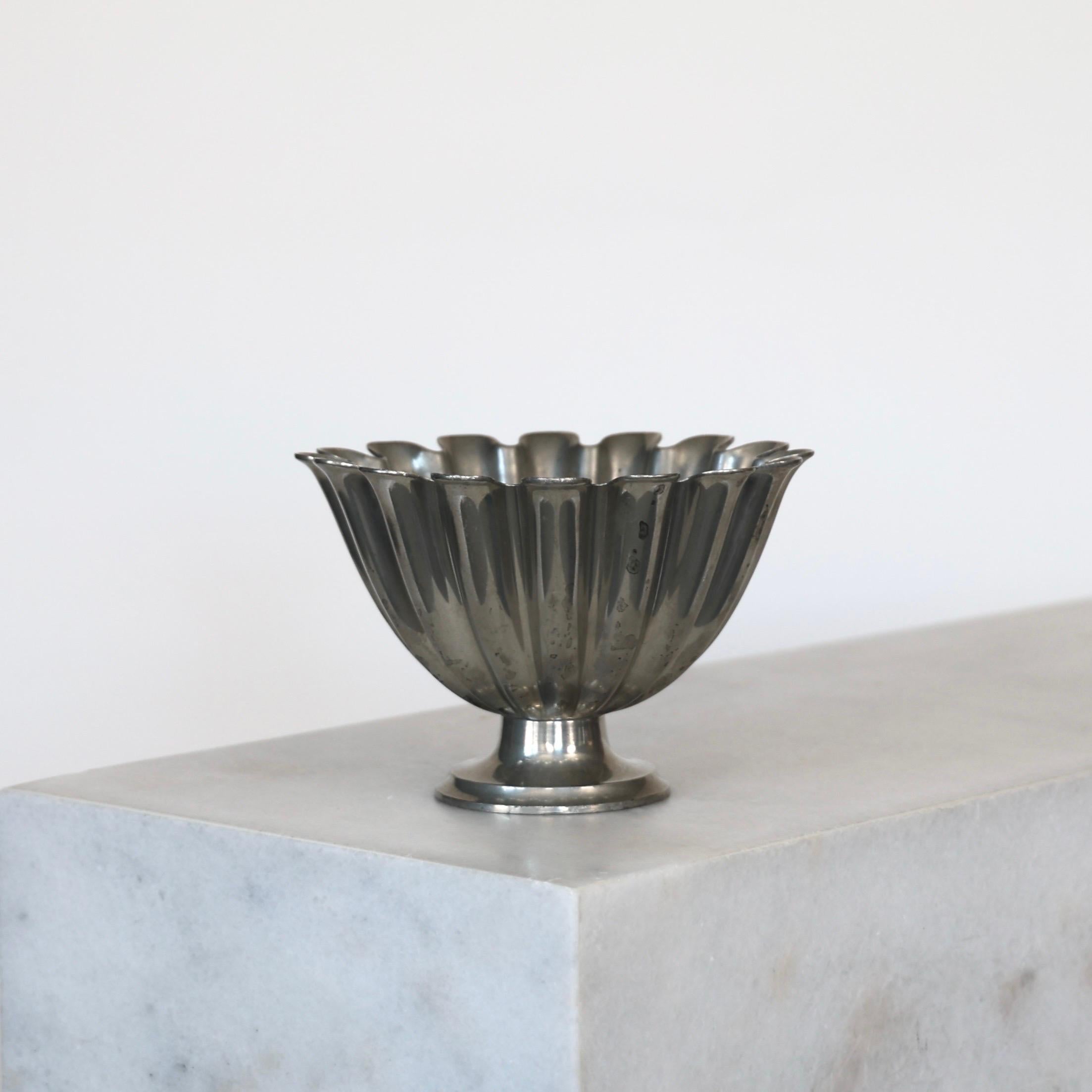 Scalloped Pedestal Pewter Bowl made by Just Andersen in the 1920s. A fine piece for a beautiful place.

* A round scalloped bowl on foot made in pewter 
* Designer: Just Andersen
* Model: 1228
* Year: 1918-1929
* Condition: Fair vintage condition.