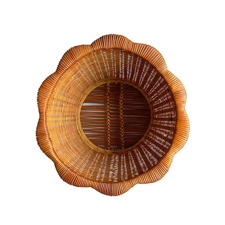 A gorgeous woven wicker and rattan basket. This piece will be great if used as a planter, storage bin, or trash bin. The edges are scalloped and wrapped in rattan. From above, it resembles flower petals. 

How We Would Style It:
Elevate a patio