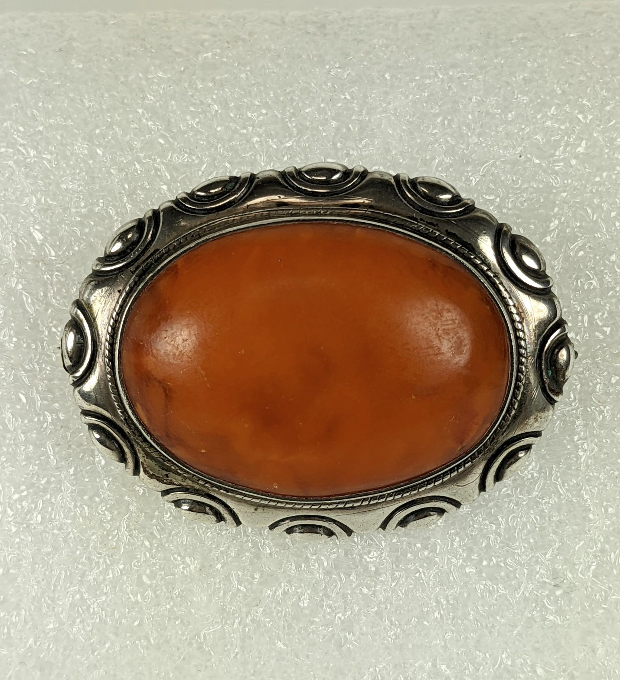 Scandanavian Skonvirke Amber Arts and Crafts Brooch from the turn of the 20th Century. Set in 800 silver with large amber oval cabochon in a repousse border. 
Signed JW, 800 silver. 2.2