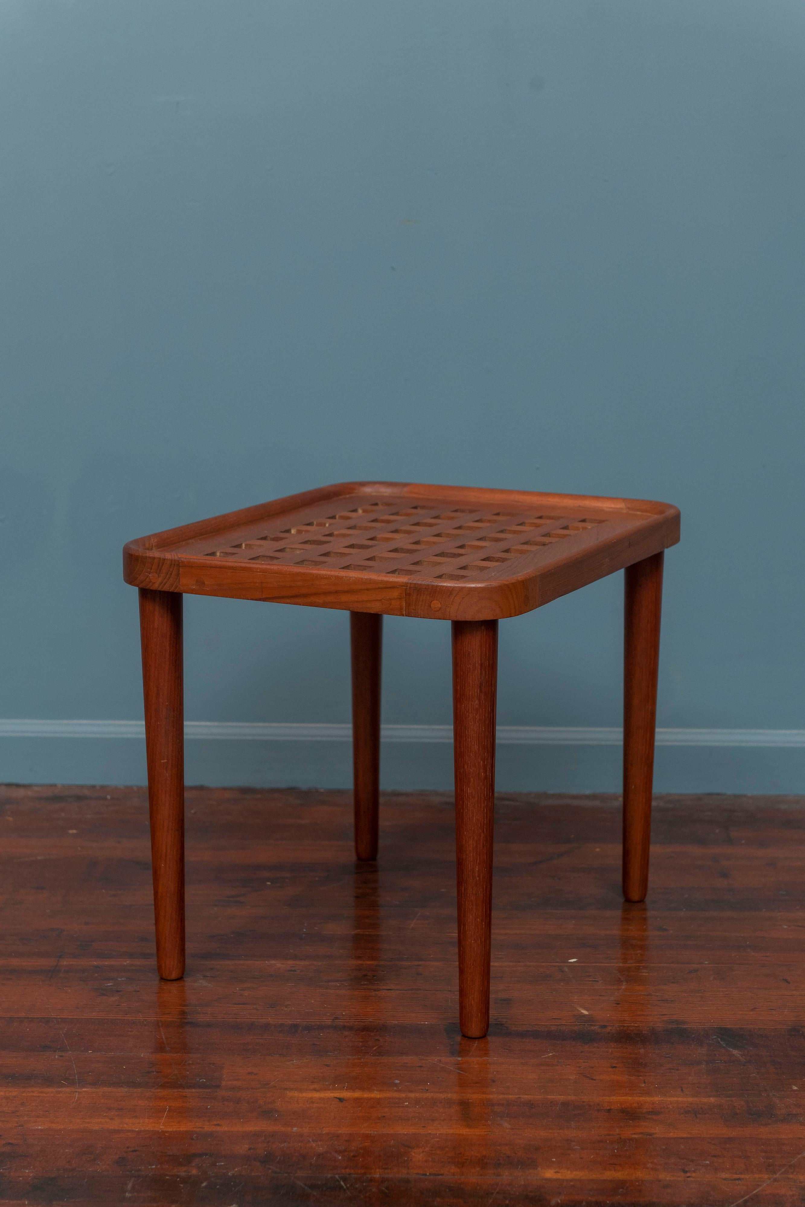 Scandanavian Modern solid teak side or end table. High quality construction and execution similar to a Jens Quistgaard serving tray with a pierced top and sculpted top edge and fixed legs. Perfect for an airy transparant interior, ready to install