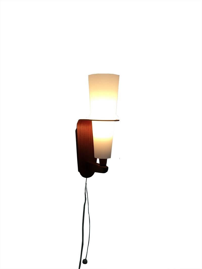 Teak with milk glass wall lamp, 1950s

Teak wooden design wall lamp with white milky glass 
The size is 32.5 cm high, 8 cm wide and the depth is 17 cm


 