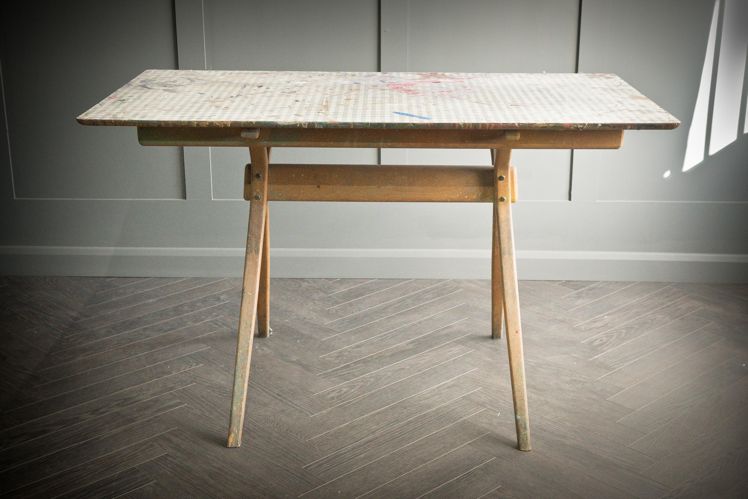 An outstanding table in true Scandinavian style - Previously used in a theater art department which shows from the paint stains to the table top. The beautiful bowed legs give the appearance of a cross frame but are four separate parts connect by a