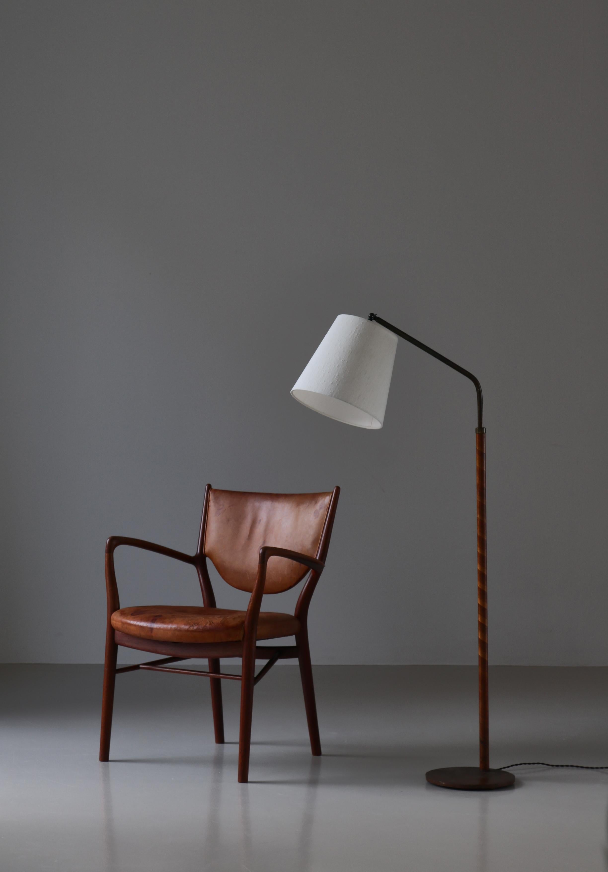 Art Deco floor lamp made in Denmark in the 1930s. The lamp is made from patinated brass and the stem is covered with birchwood veneer. Equipped with a new shade in light linen. The lamp is adjustable in height, position and