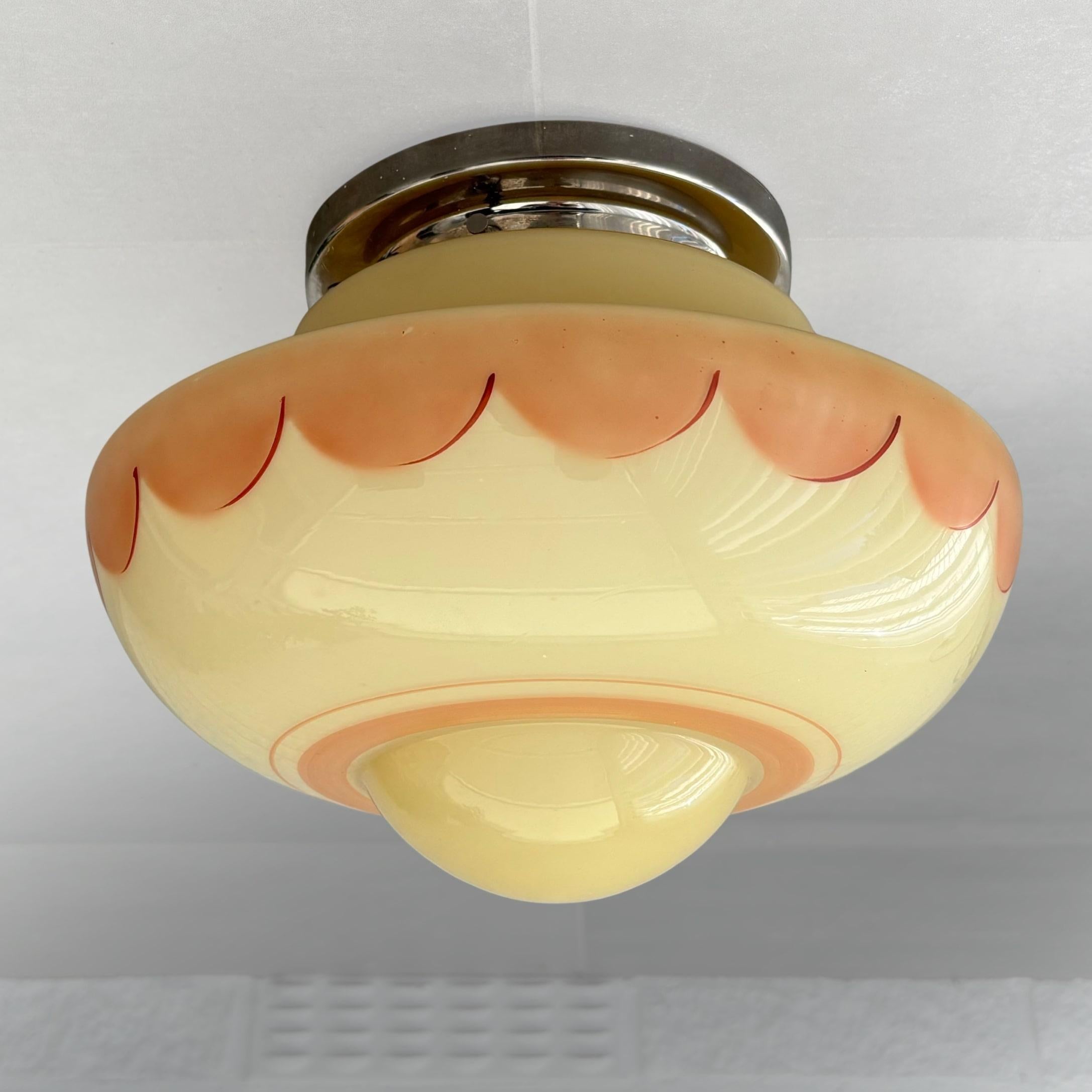A charming Scandinavian Art Deco flush mount ceiling lamp, produced by an unidentified Swedish manufacturer in the 1930s. The lamp features a softly contoured glass shade in a warm yellow tone, delicately adorned with a pink hand-painted pattern