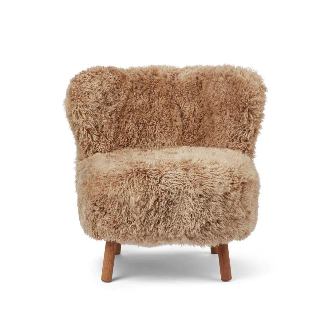 Realizzata su misura in Danimarca, questa poltrona lounge in pelle di pecora è l'emblema del lusso e del comfort. Rivestita con la migliore pelle di pecora neozelandese a pelo lungo, questa sedia non solo è incredibilmente morbida, ma aggiunge anche