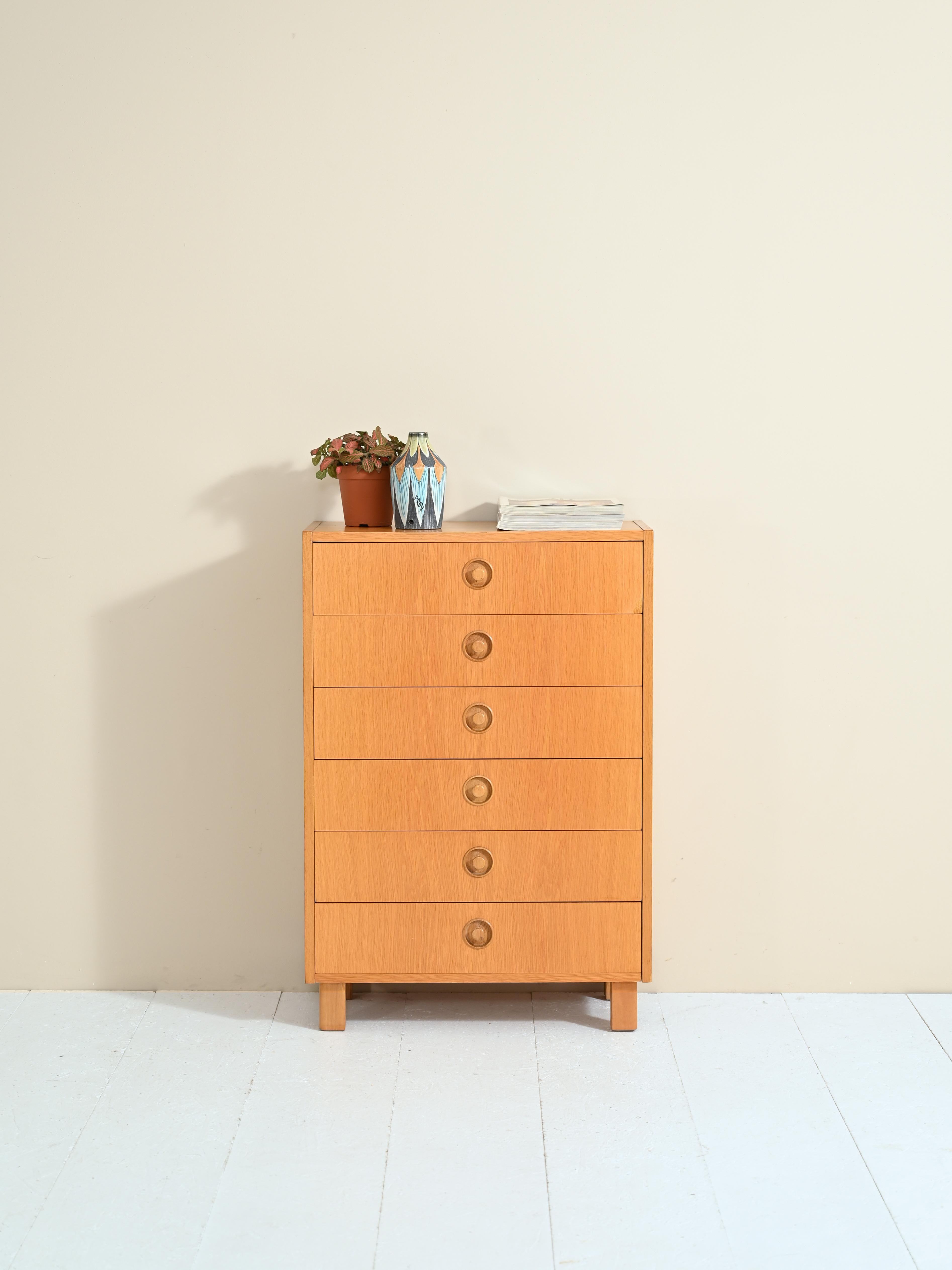Vintage Scandinavian-made 1960s cabinet with six drawers.
Simple, linear forms for this chest of drawers in warm oak wood tones.
The distinctive handle of the drawers carved into the wood is the distinguishing feature of this cabinet.

Good