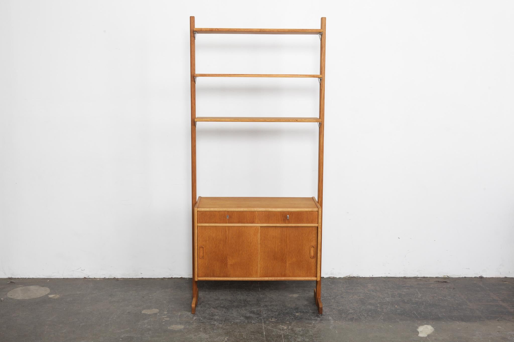 Newly refinished free standing Scandinavian oak shelves with storage cabinet below that have 2 sliding doors and 2 locking drawers. Most likely Sweden, 1960s. Fully finished on both sides so it can float in a room. Top shelves measure 31. inches